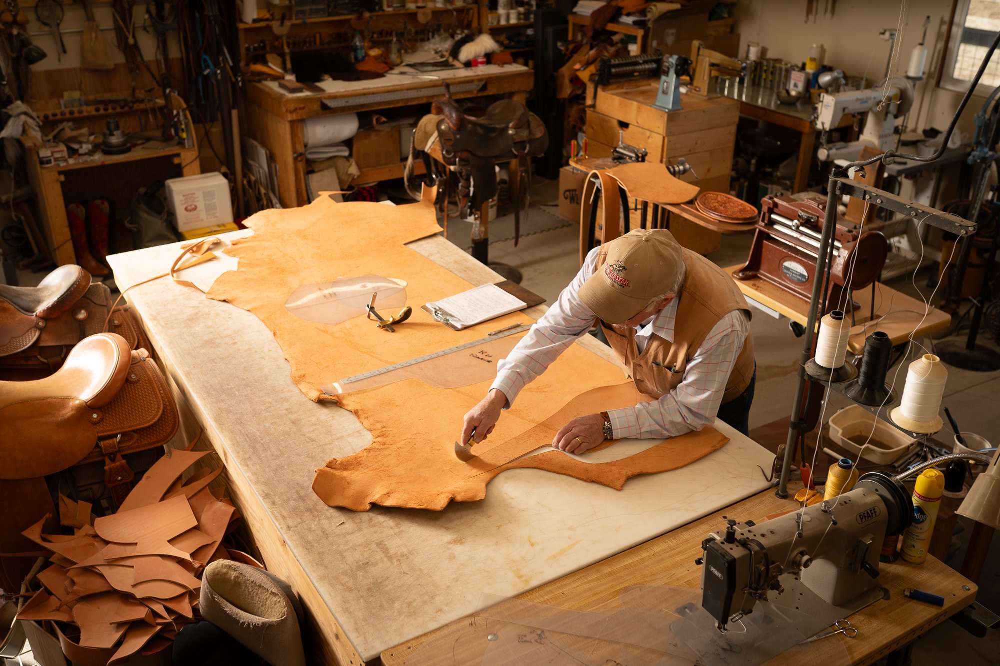 Western saddle maker Doug Cox cutting leather in his workshop