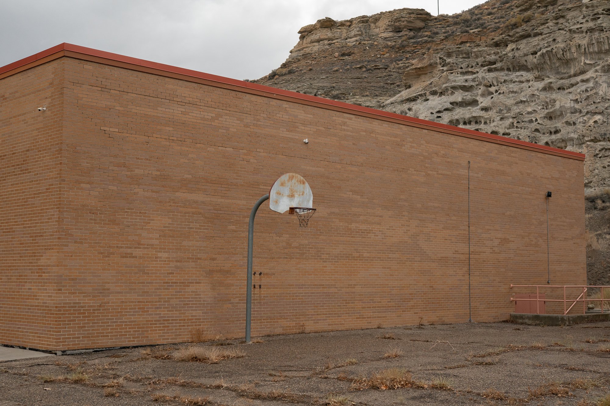 Rusted basketball hoop beside large brick building in Rock Springs Wyoming