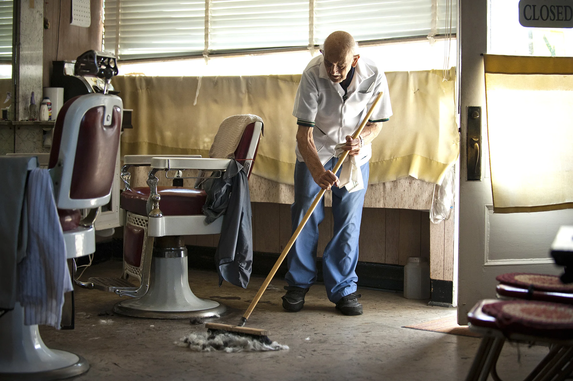  Photograph of an old barber sweeping up a pile of hair in his traditional barbershop in Greenwich, Connecticut. This image is part of a long-term documentary project available for editorial and commercial licensing and cultural exhibitions. 