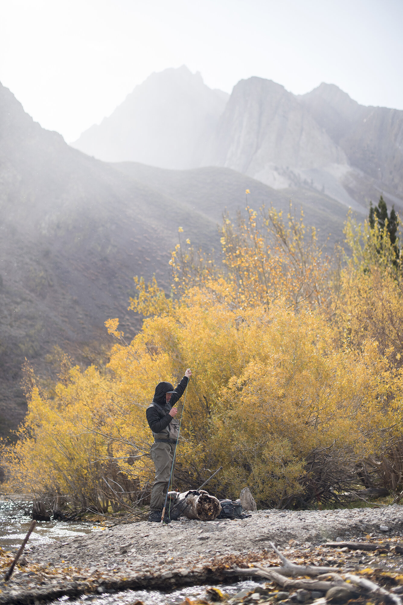  A fly fisherman prepares his gear in front of fall colors and a mountain backdrop.  