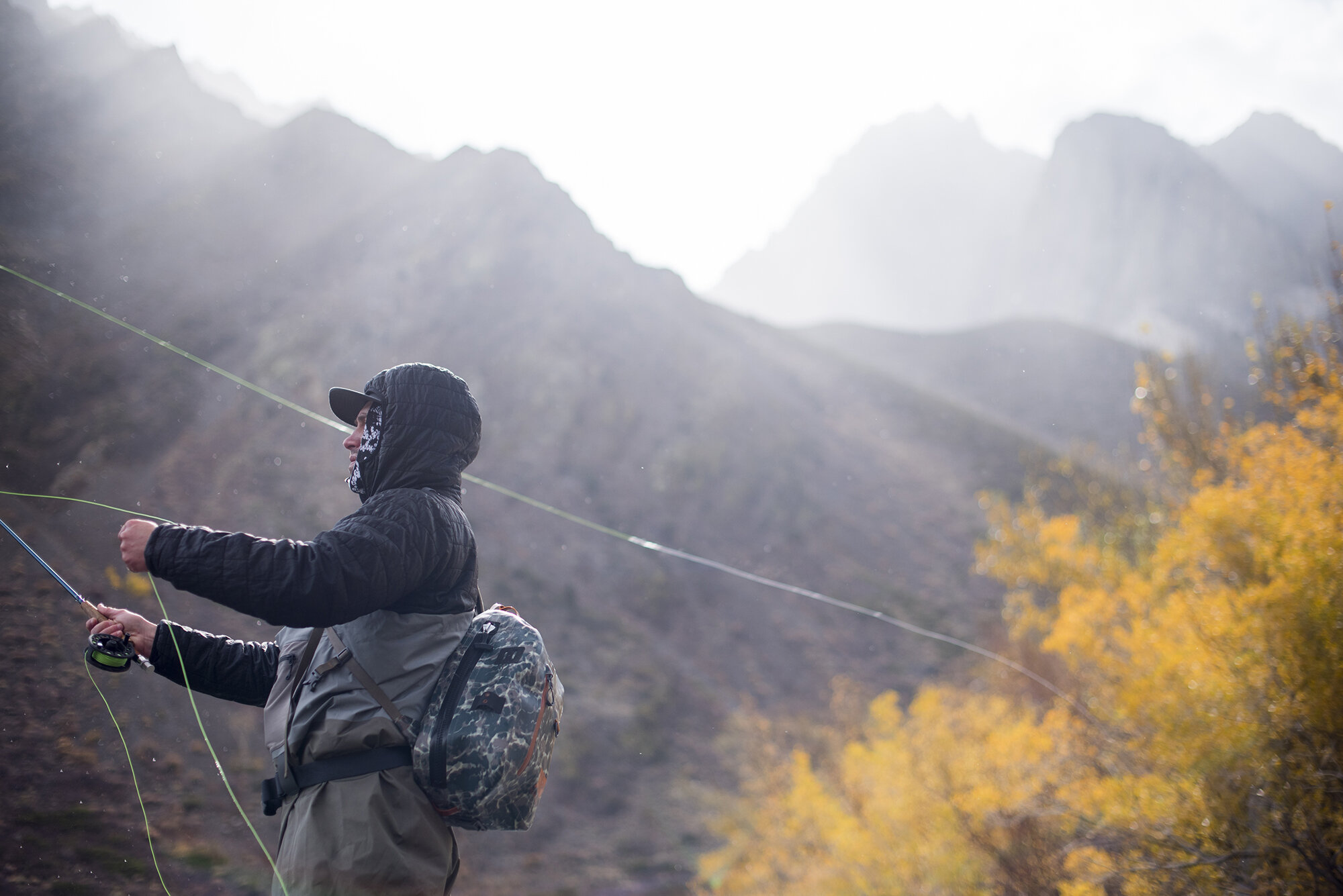  A fly fisherman casting in front of a mountain backdrop.  