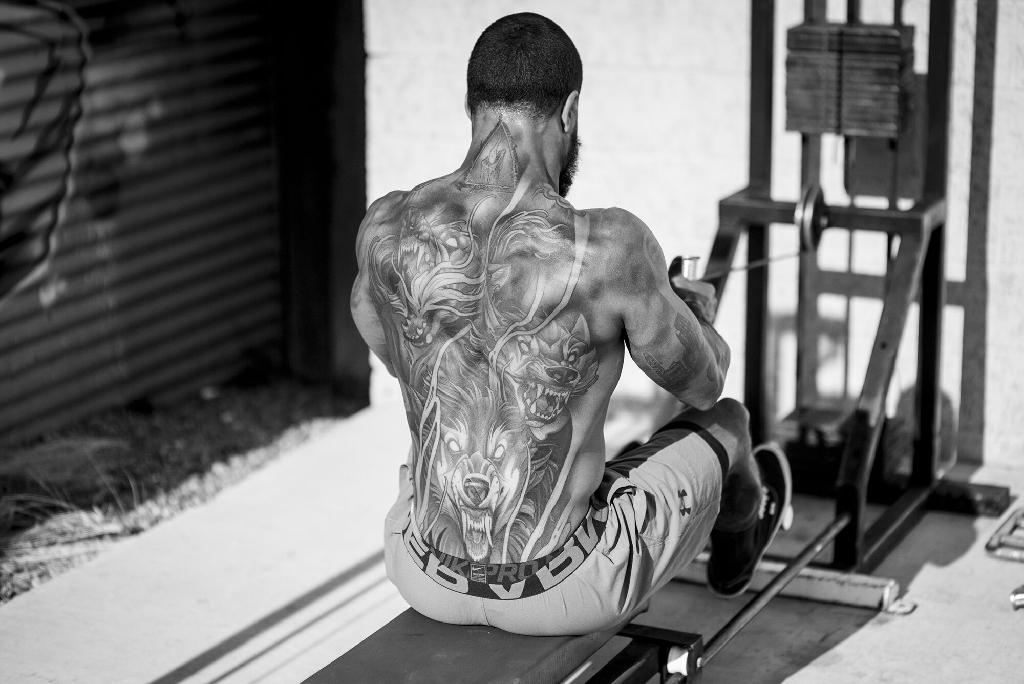  A tattooed athlete working on a back machine.  