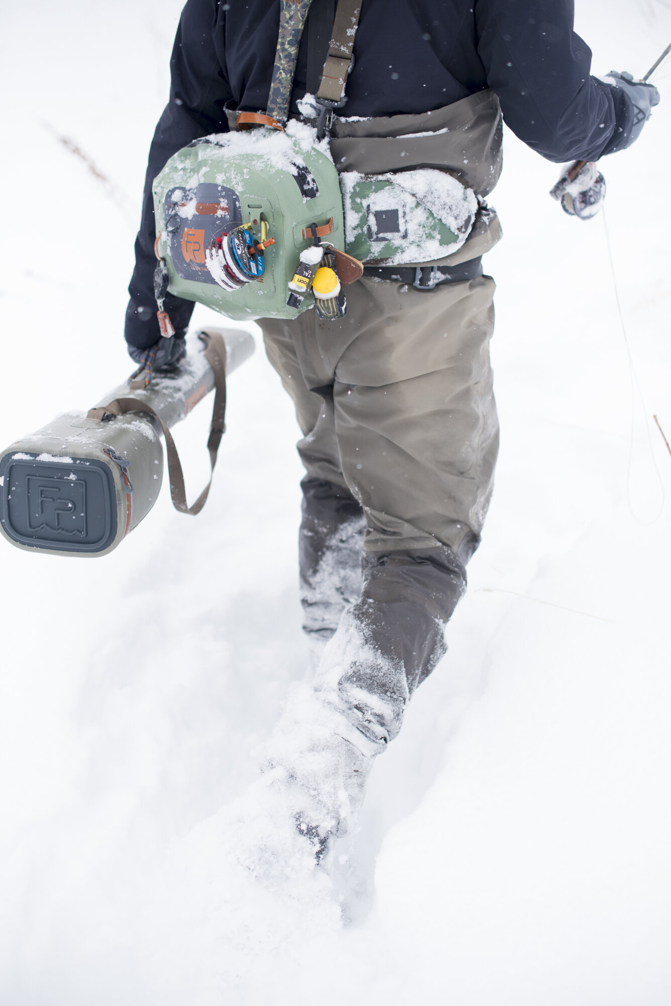  A fly fisherman walking through deep snow with all his gear in Colorado.  