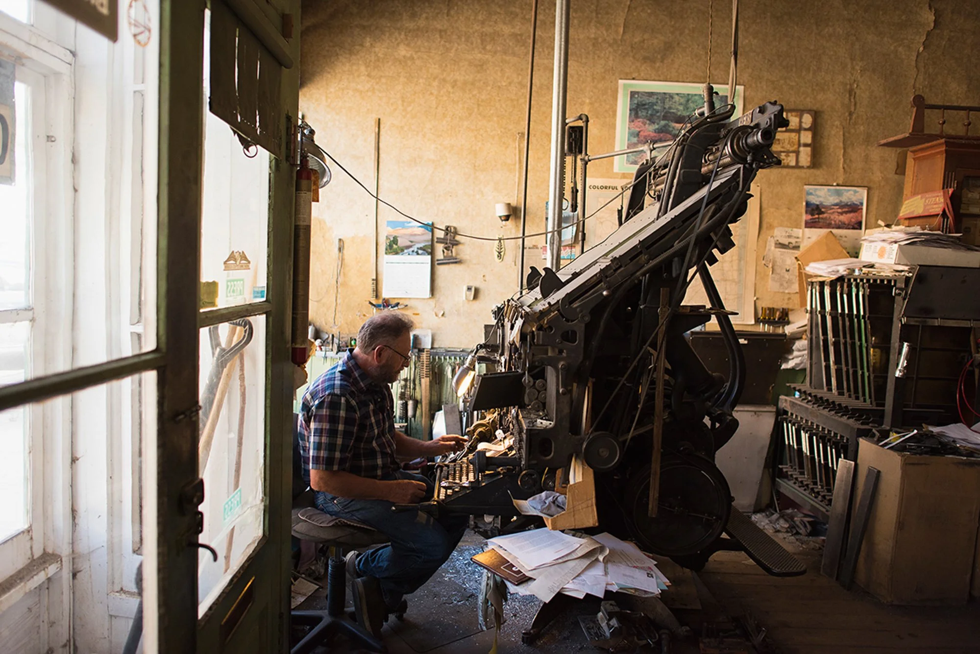 Dean Coombs operating the Linotype machine inside the Saguache Crescent