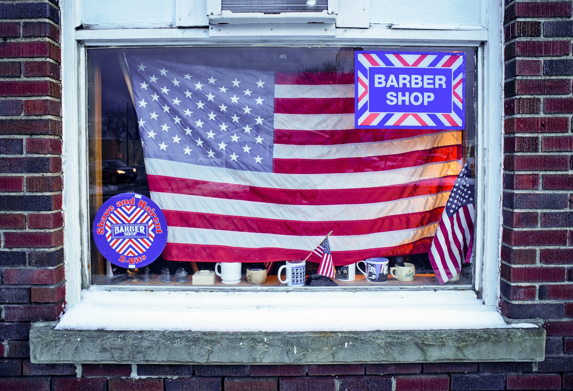  Photograph of an American Flag hanging in the window of a barbershop in rural Pennsylvania  