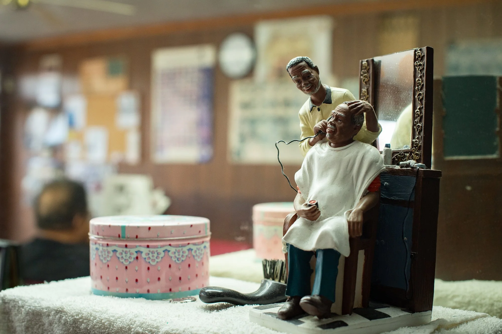 Small figurine of a barber cutting hair placed on a towel inside a barbershop