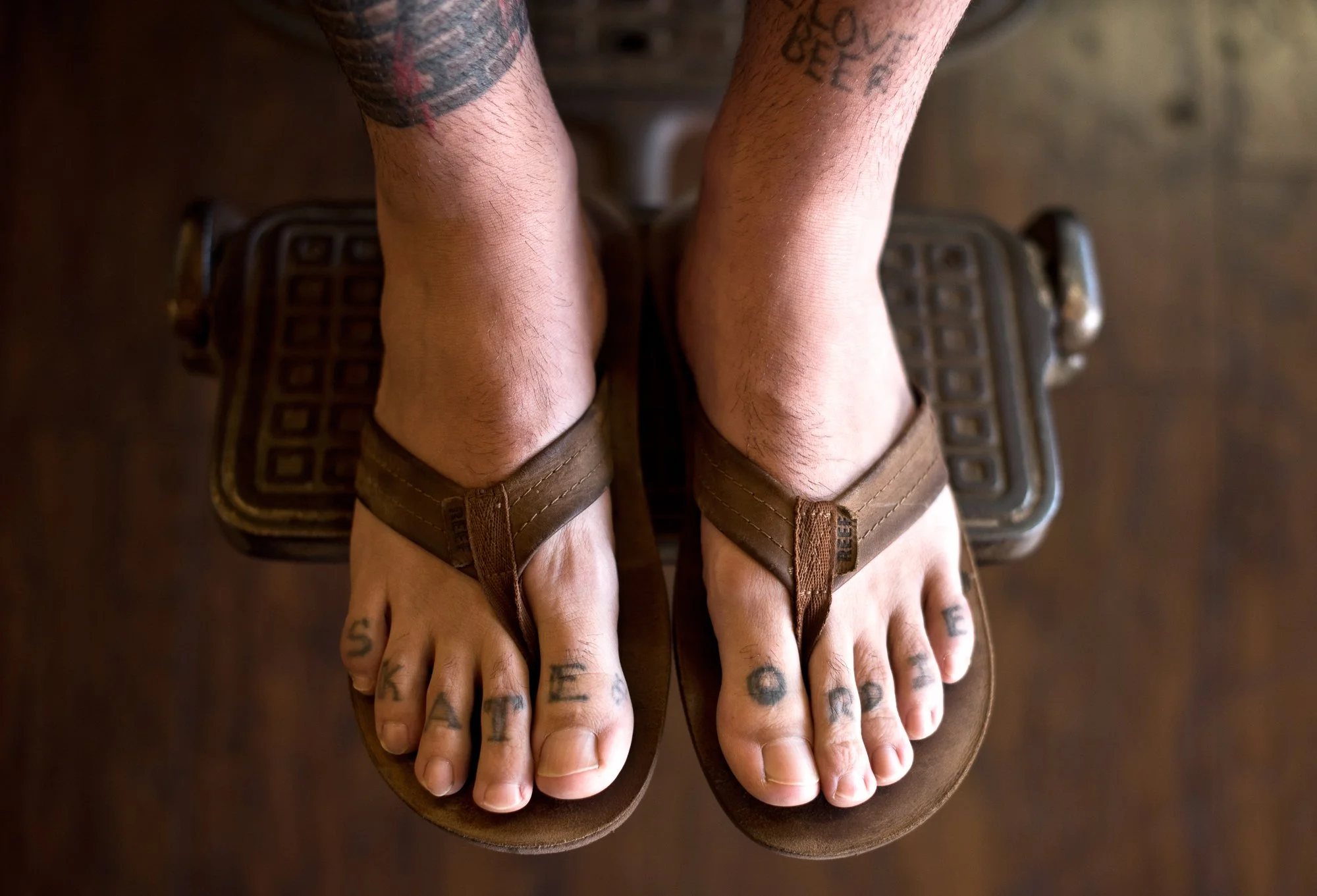  Photograph of a persons feet in a barber chair with a tattoo that reads Skate or Die  