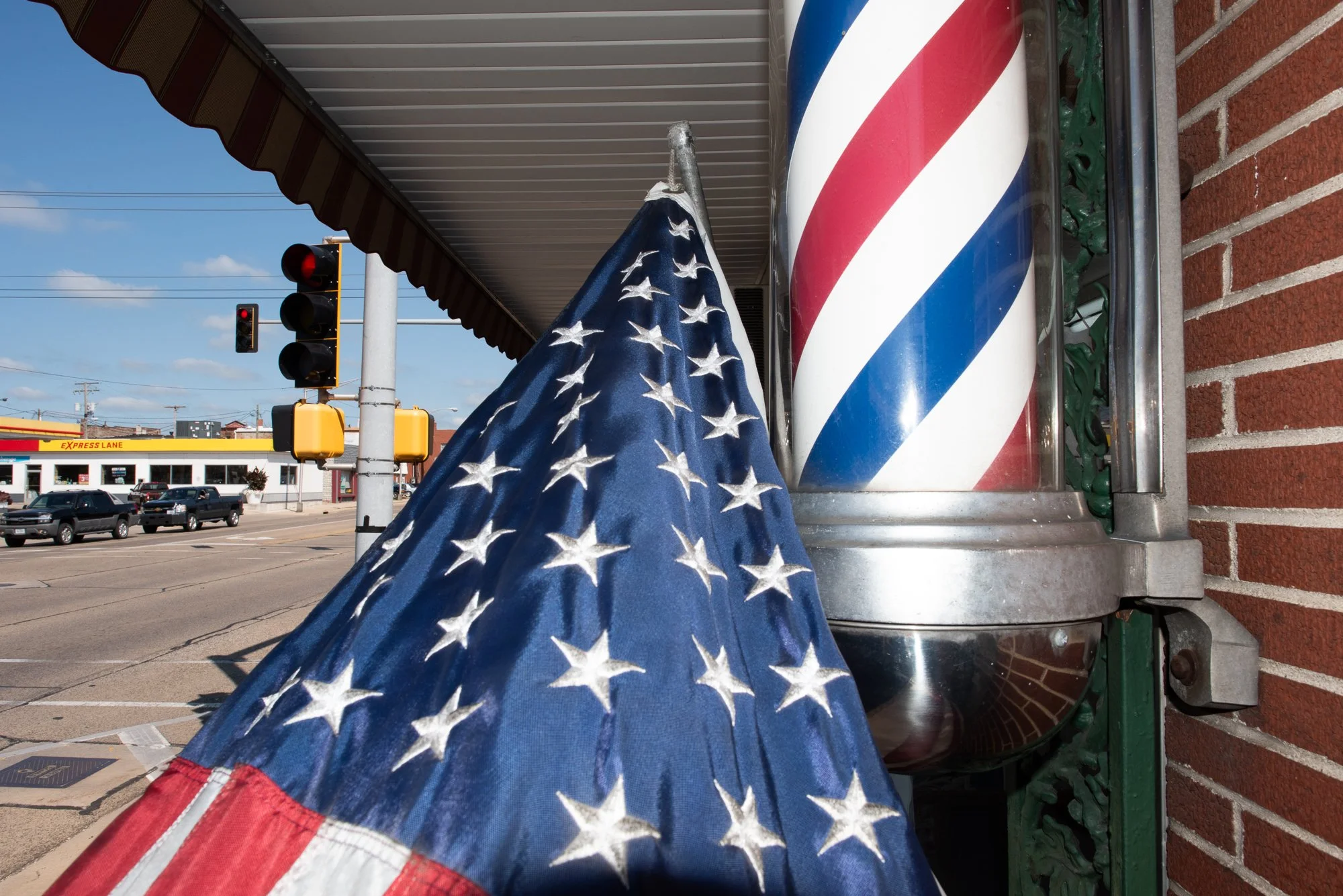  Photograph of a barber pole and American flag hangin in front of a traditional barbershop in Rock Island, Illinois  
