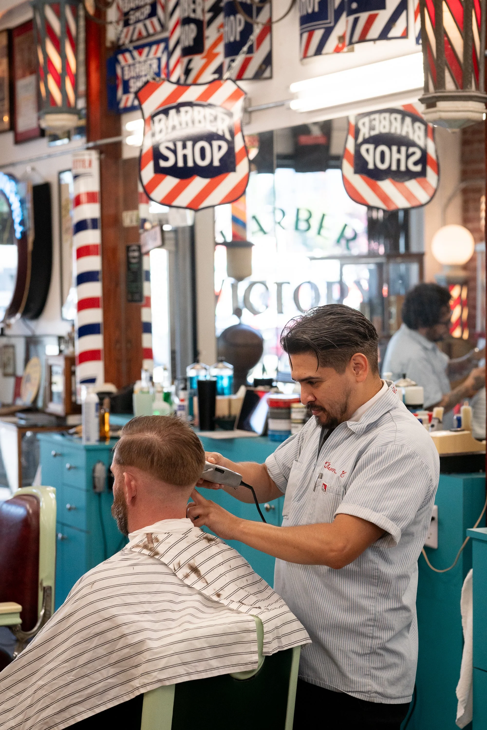  Photograph of a barbershop with lots of antique poles and signage.  Part of a documentary photographer series about traditional barbershops in all 50 states of America.  