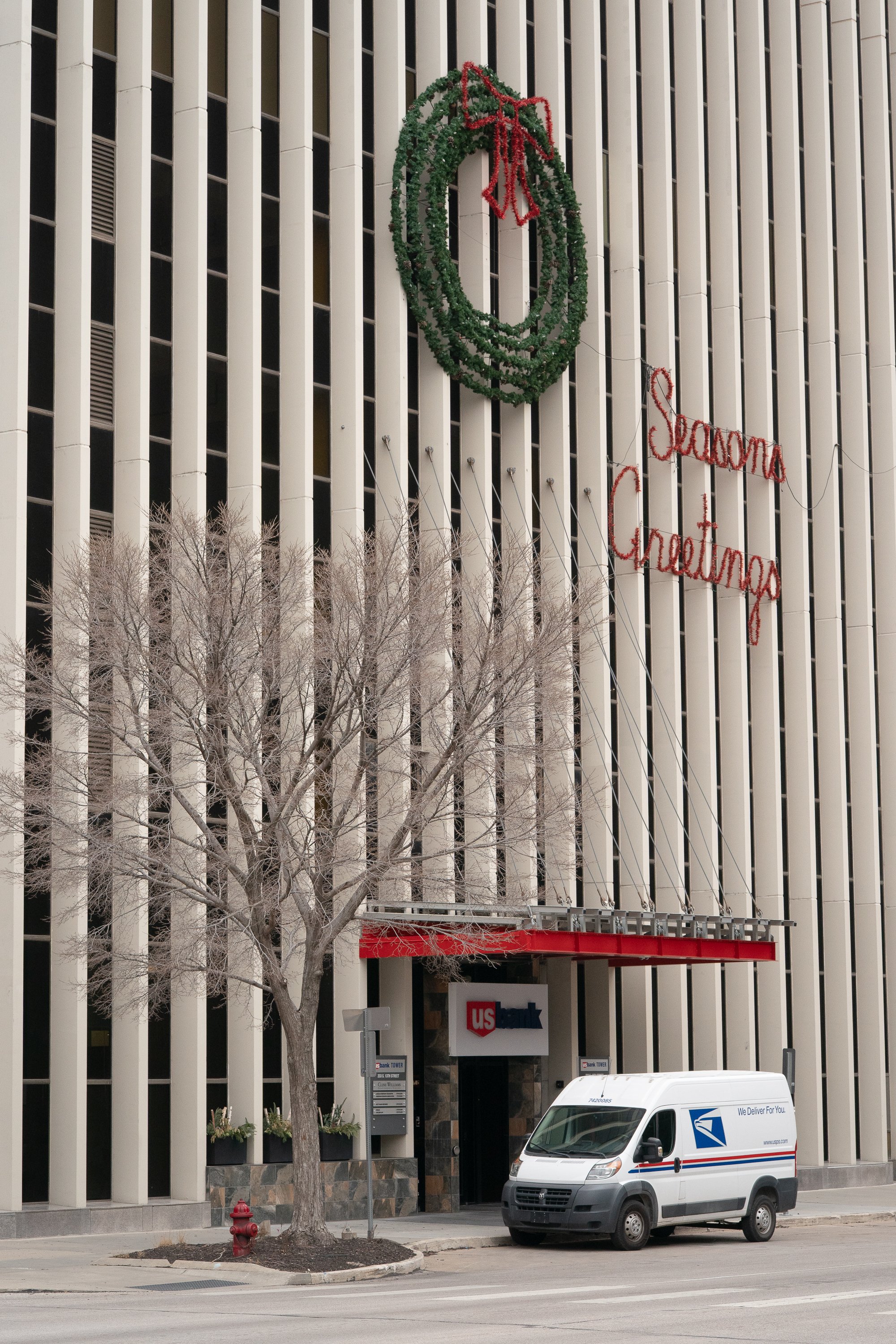  A color documentary photograph of a downtown office building decorated with a large holiday wreath. The image captures American commercial architecture and seasonal decoration within an urban streetscape - Omaha, Nebraska - 2025 