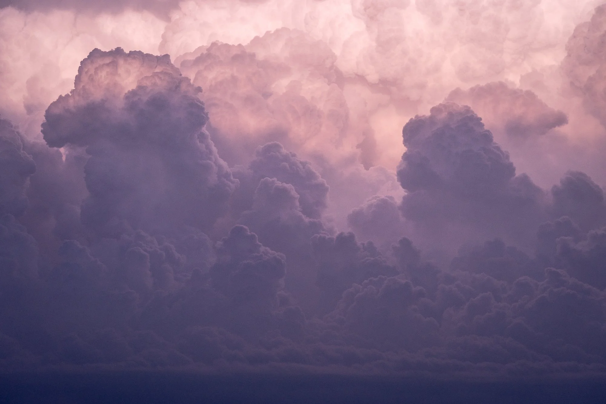  A dense formation of clouds fills the frame, illuminated by warm evening light that softens their scale and weight. The photograph becomes an abstract meditation on form, volume, and atmosphere. 