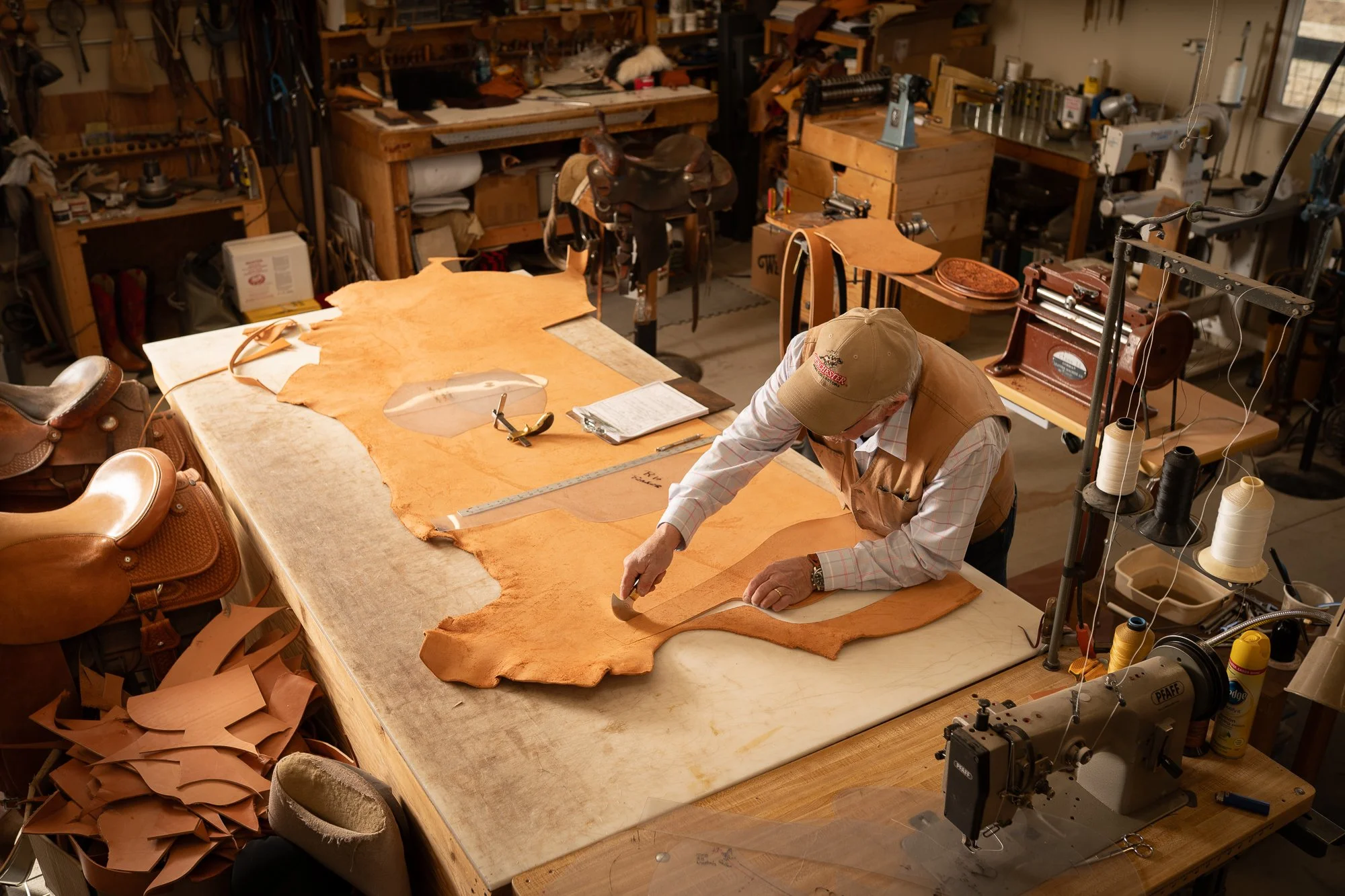  Inside the workshop of a traditional western saddle maker as he cuts leather for a saddle 