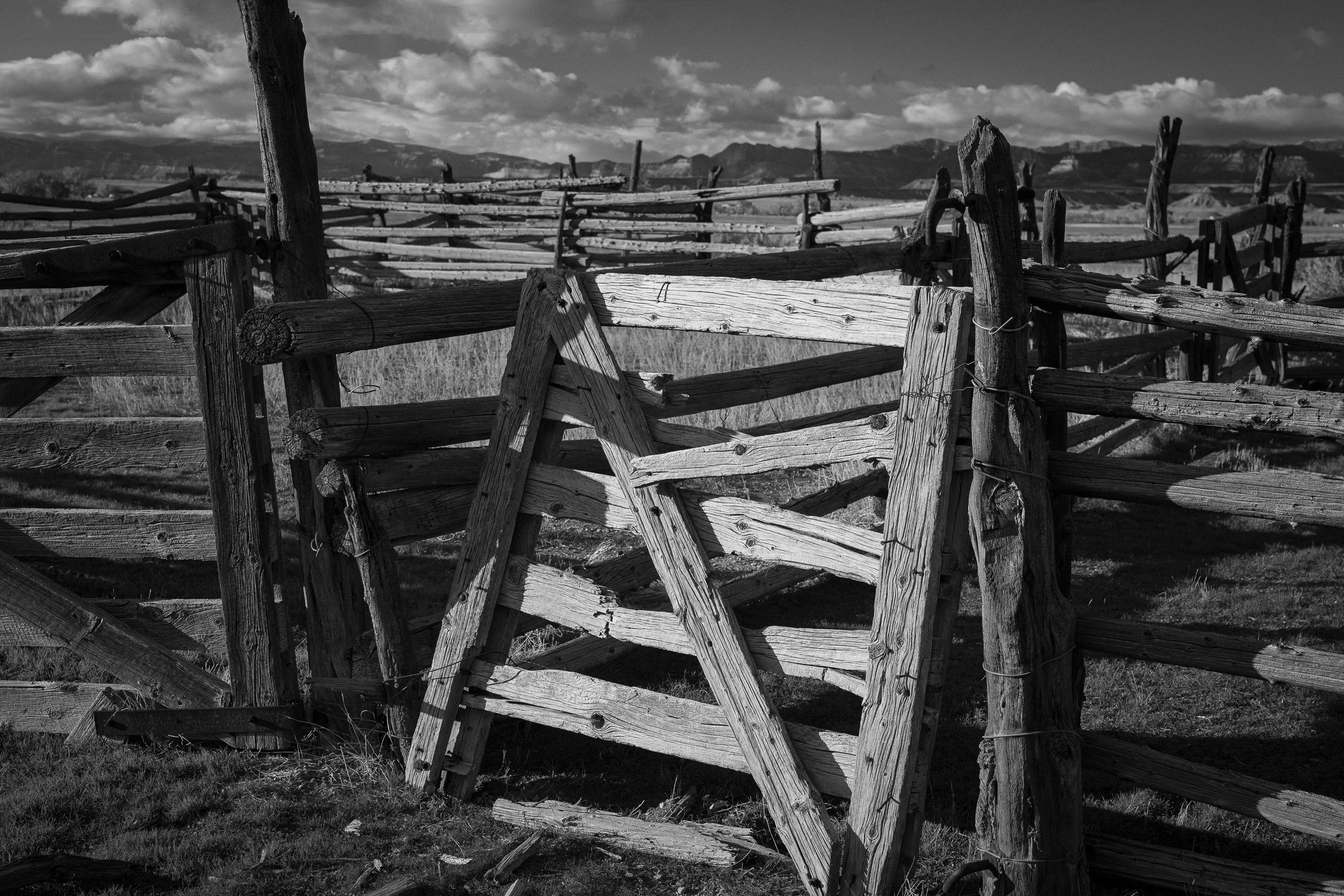  Close-up of a weathered wooden gate with layered textures and distant mountains beyond. 