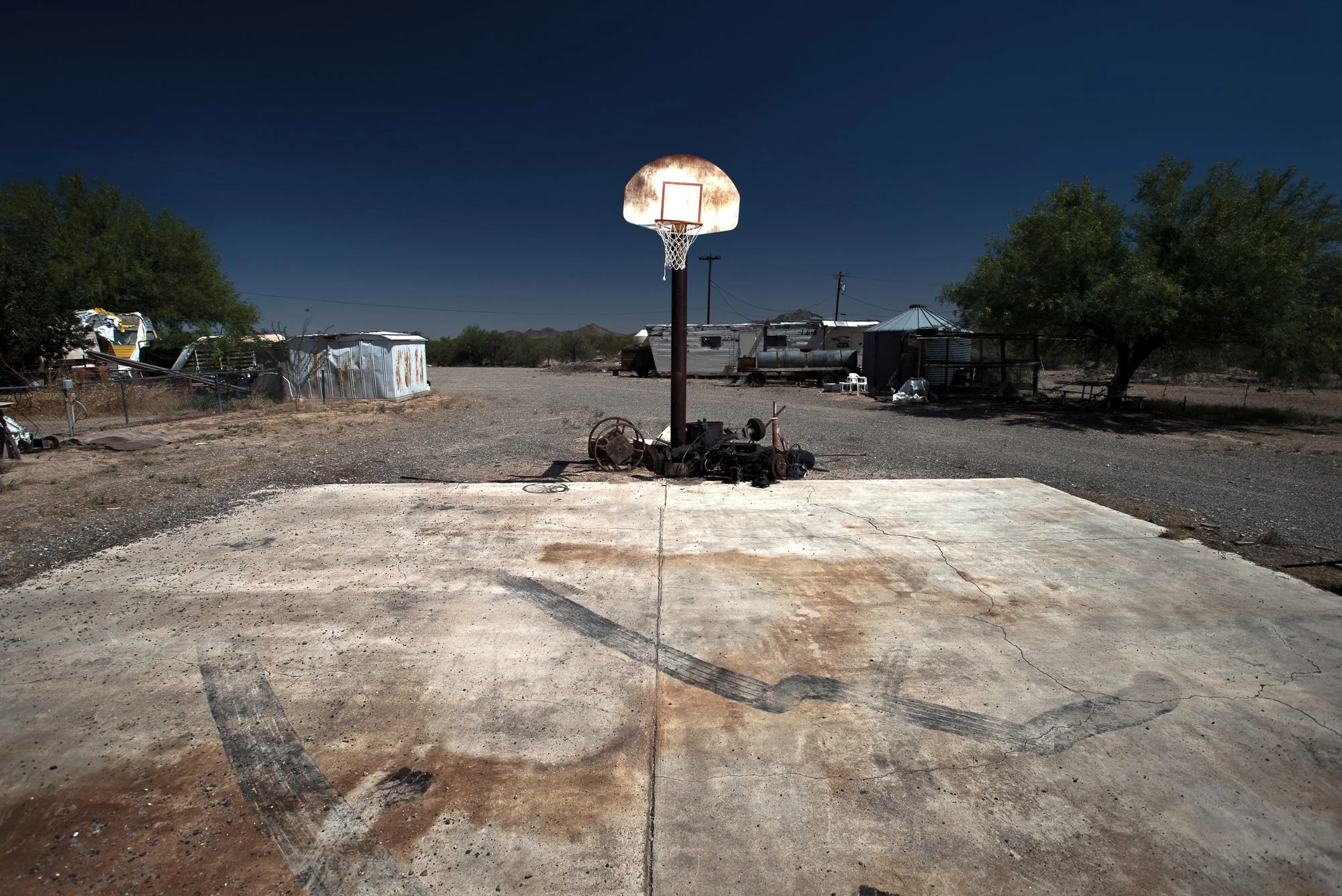 Basketball hoop beside a worn concrete court in a desert yard