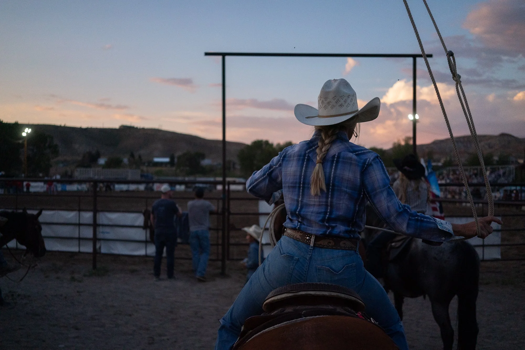 Cowgirl on horseback waits near the arena with a rope as the rodeo continues in Dubois Wyoming