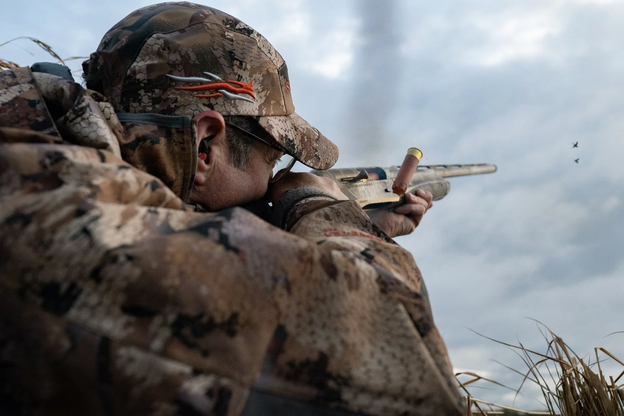 A duck hunter aims his shotgun at flying birds during waterfowl hunting season in Ontario