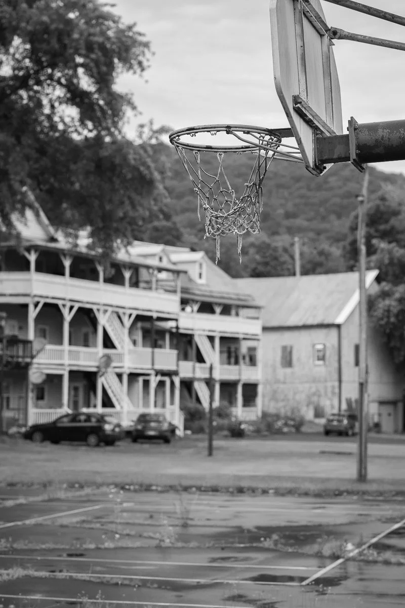 Black and white photograph of a basketball hoop in a small New England town