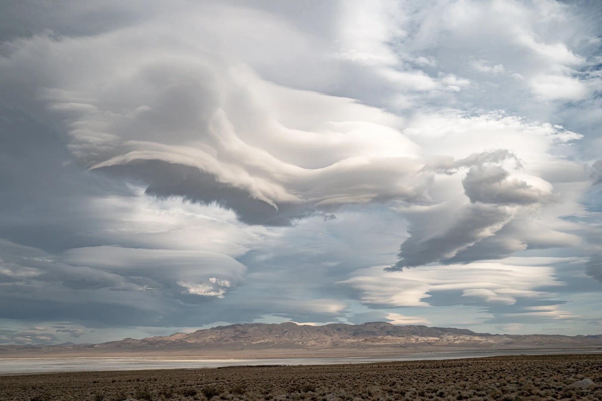 Expansive desert landscape with dramatic cloud formations over vast basin