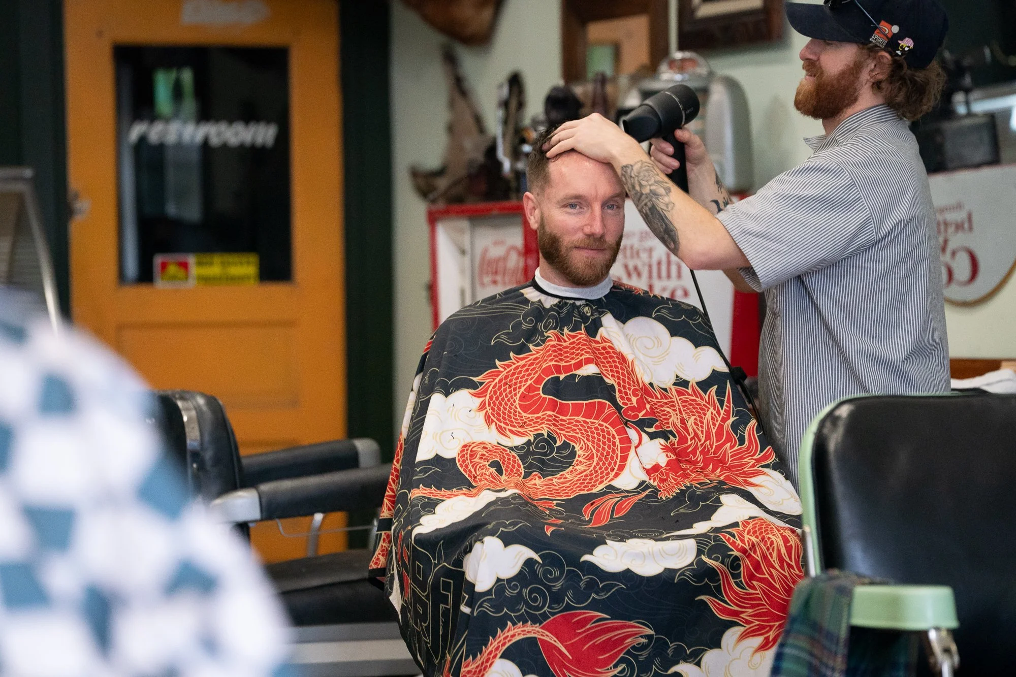 barber blow drying a client’s hair inside Belmont Barbershop in Boise Idaho