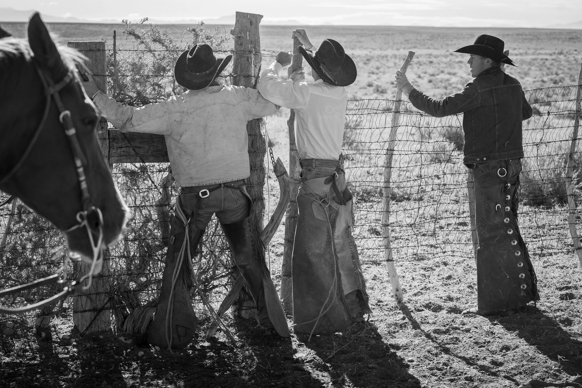 Cowboys repairing barbed wire fence on a remote cattle ranch in the American West