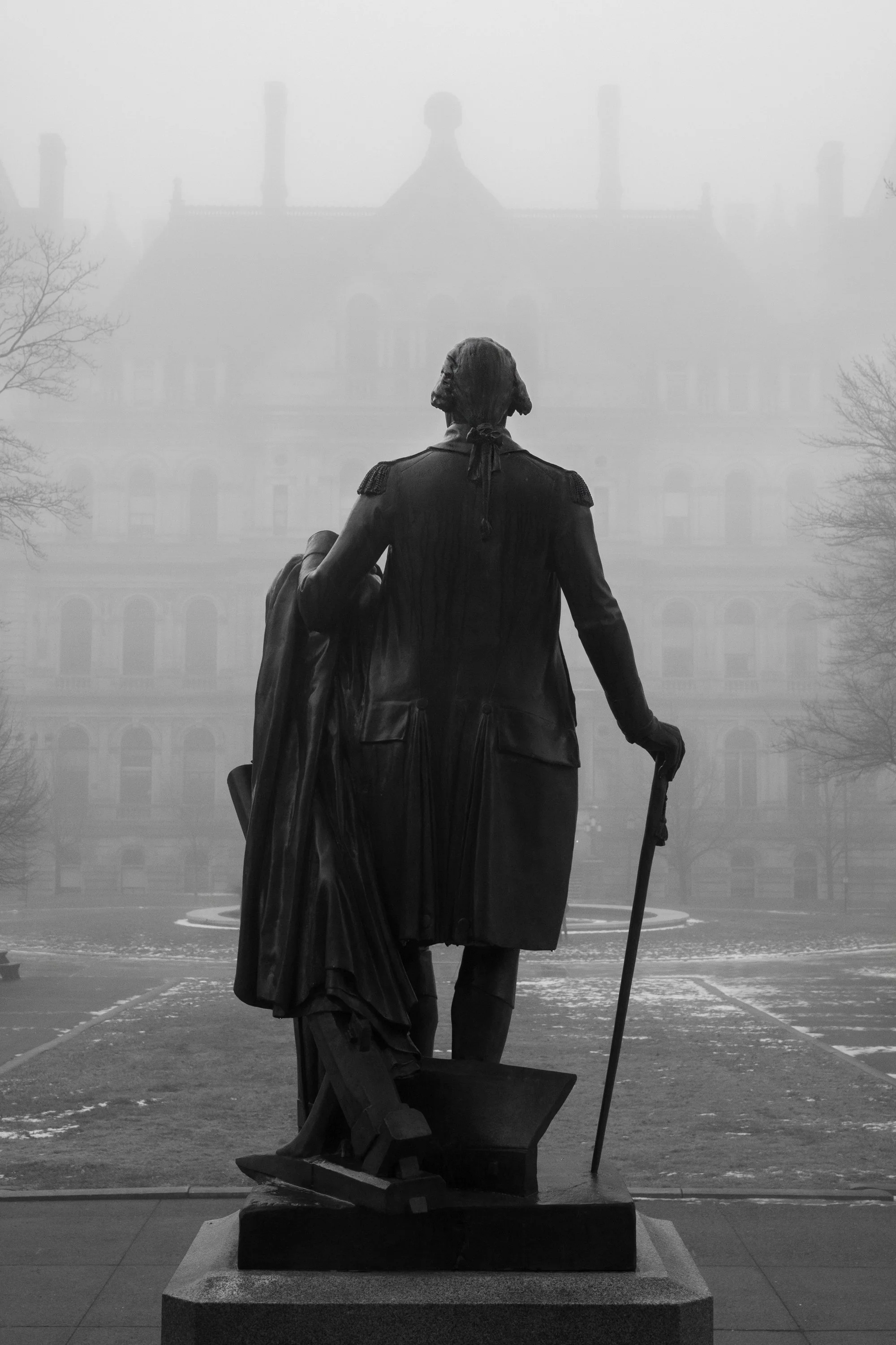Black and white photograph of a statue in Washington Park framed by bare tree branches in Albany