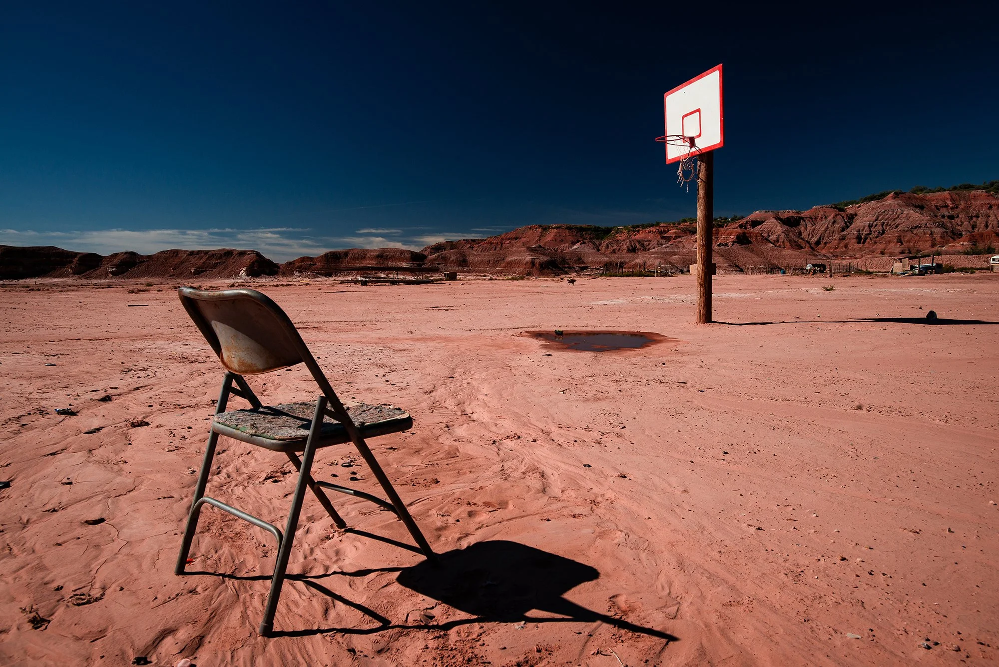 Basketball hoop and folding chair on a red desert court