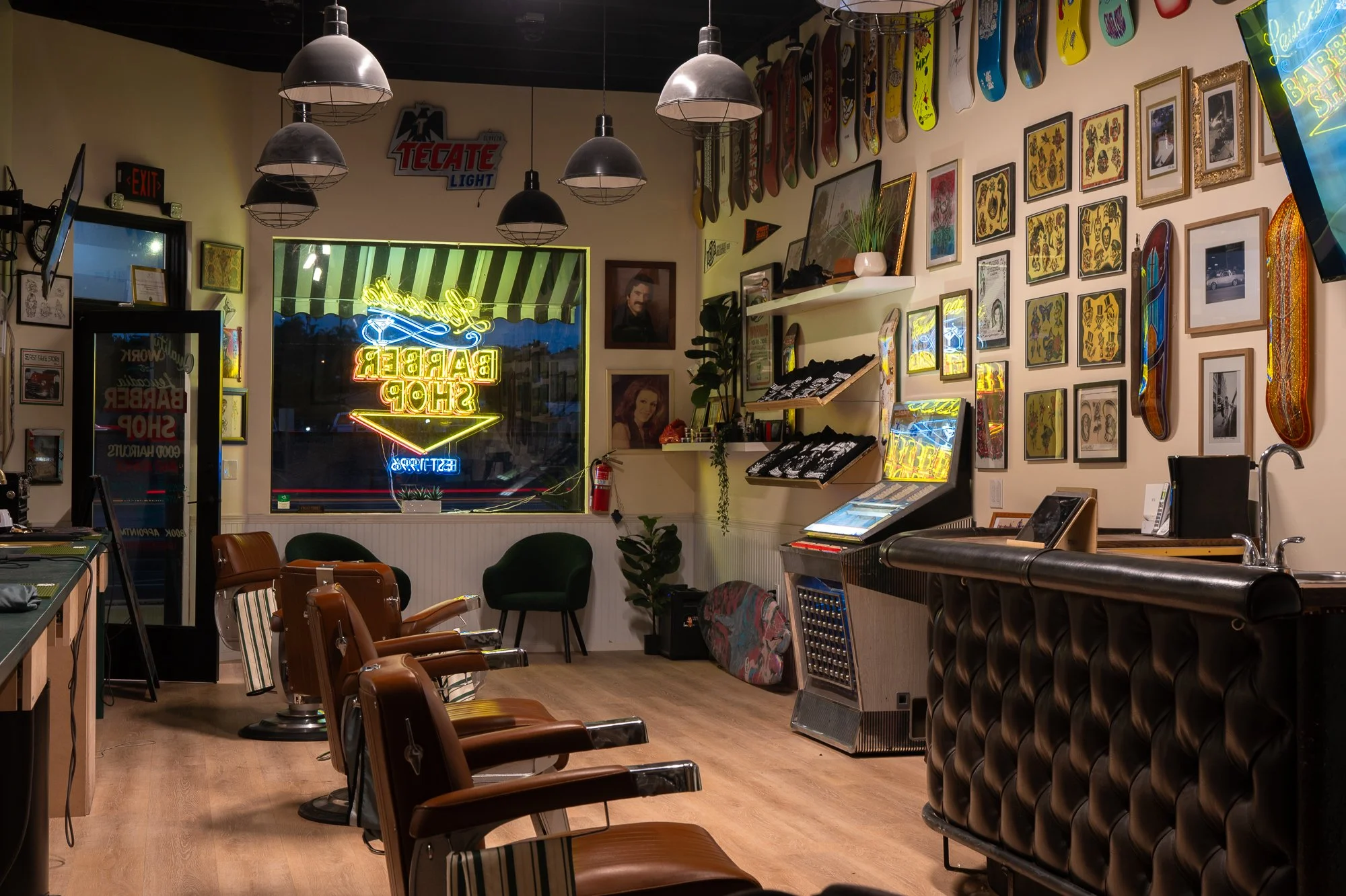 Interior of Leucadia Barbershop in Encinitas, California showing barber chairs, framed artwork, and skateboards.
