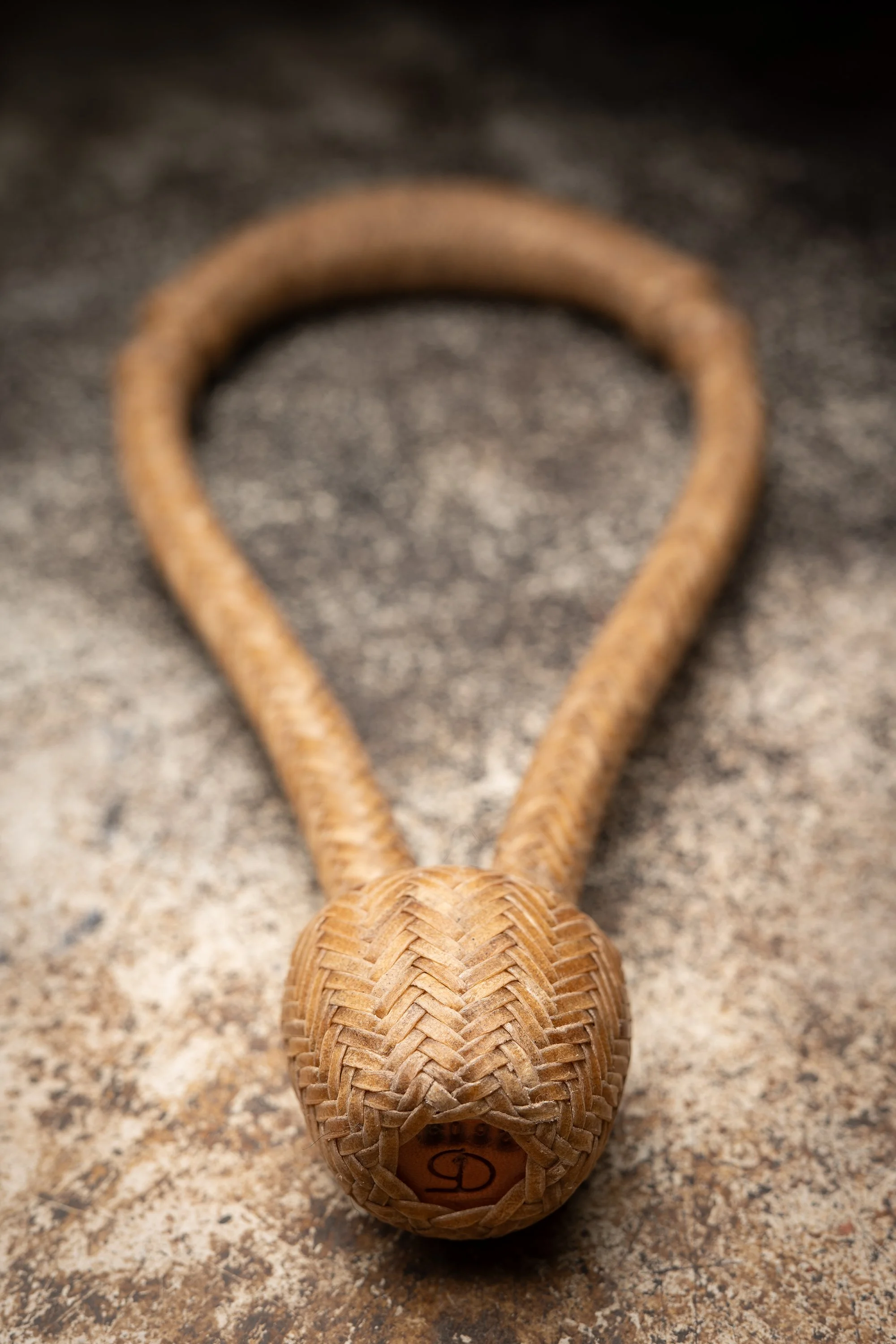 A close-up of a finished handmade rawhide bosal showing intricate braided patterns and craftsmanship