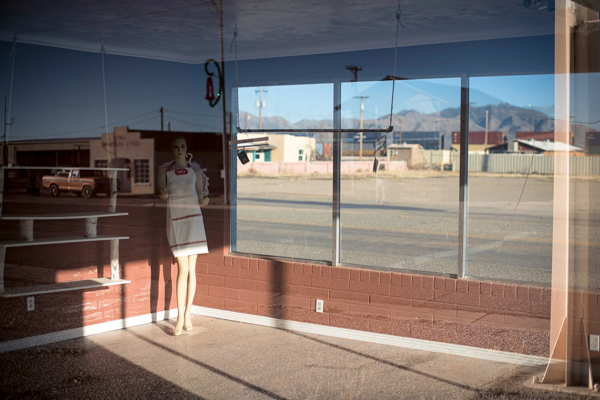 Empty storefront interior with mannequin and reflections of small town street in American West