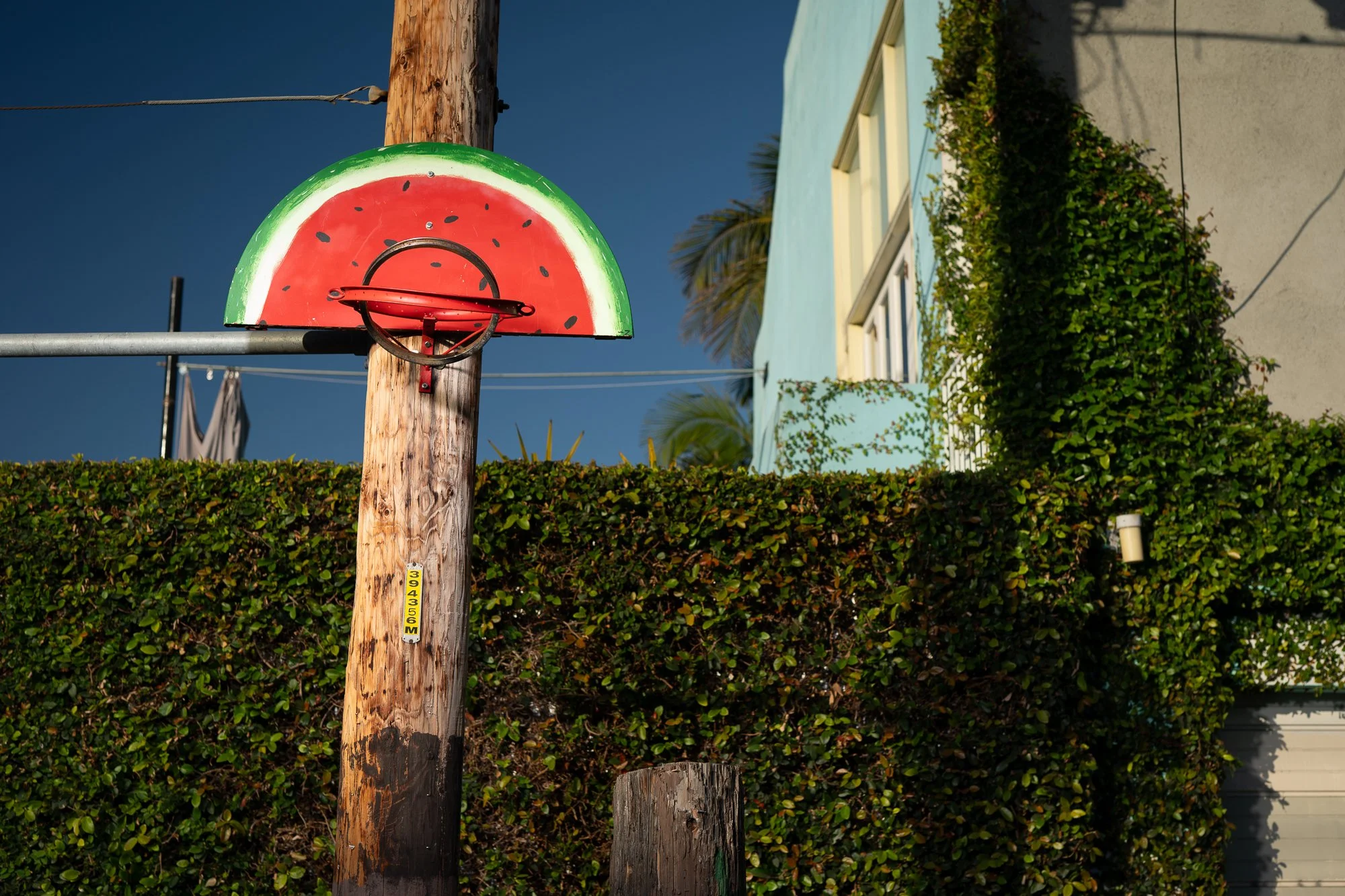 A basketball hoop made from junk with a backboard painted to look like a watermelon