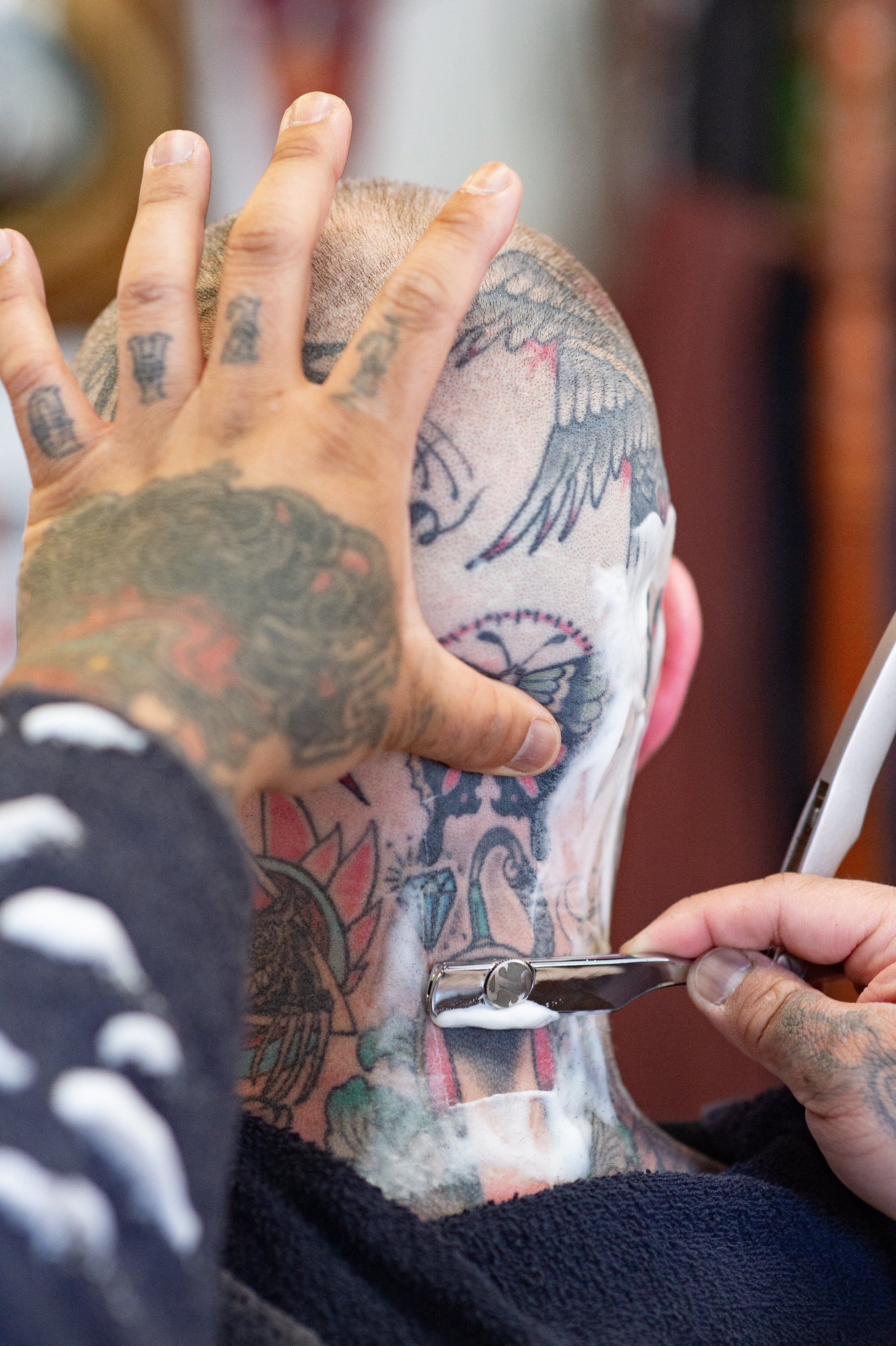 straight razor shave on tattooed head inside Shane's Barbershop San Mateo