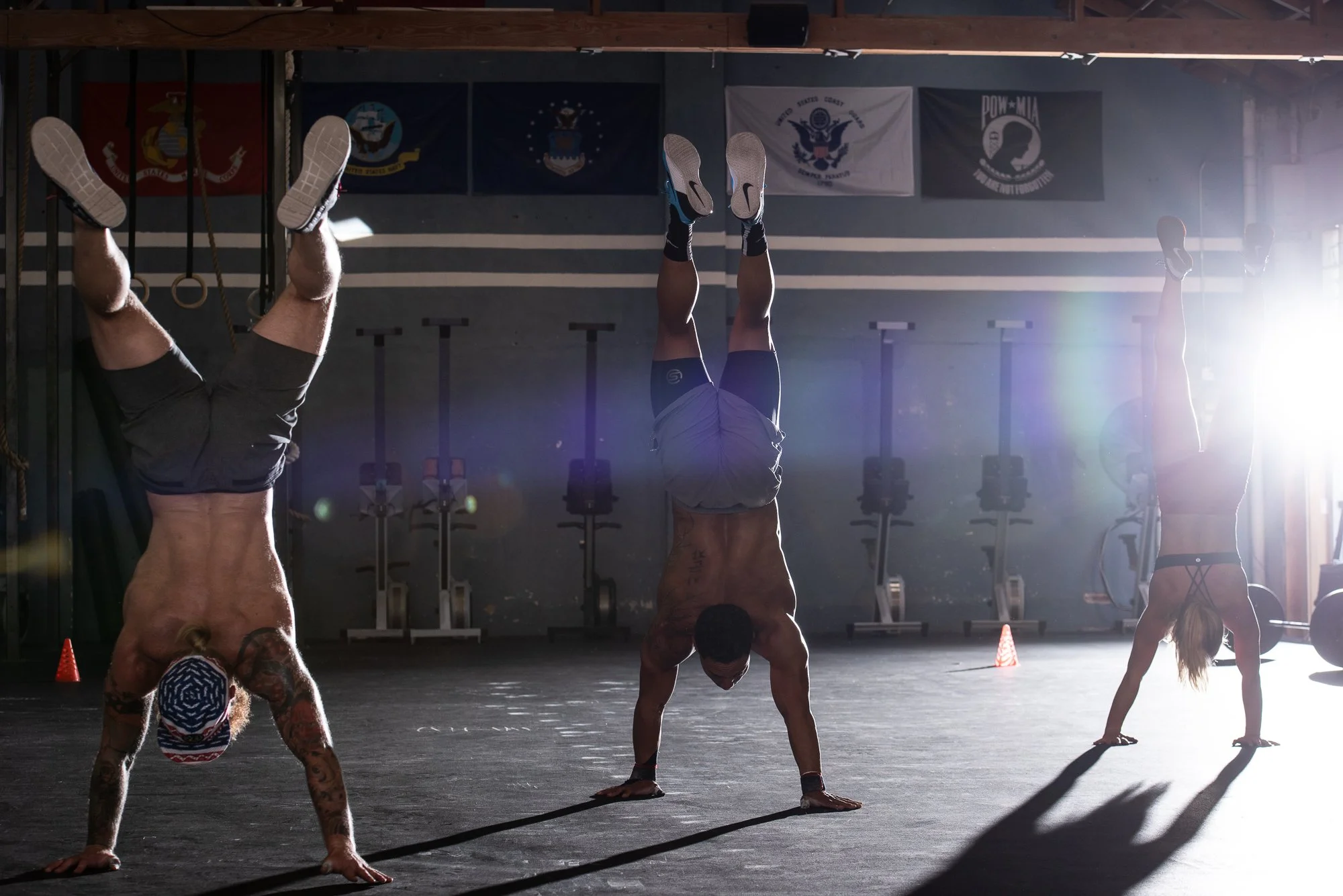 Three CrossFit athletes performing handstands on a gym floor in Boulder, Colorado.