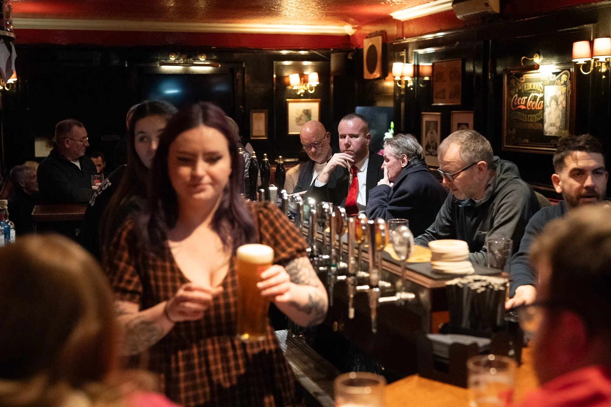 Bartender serving pint of beer inside The Bailie Bar in Edinburgh