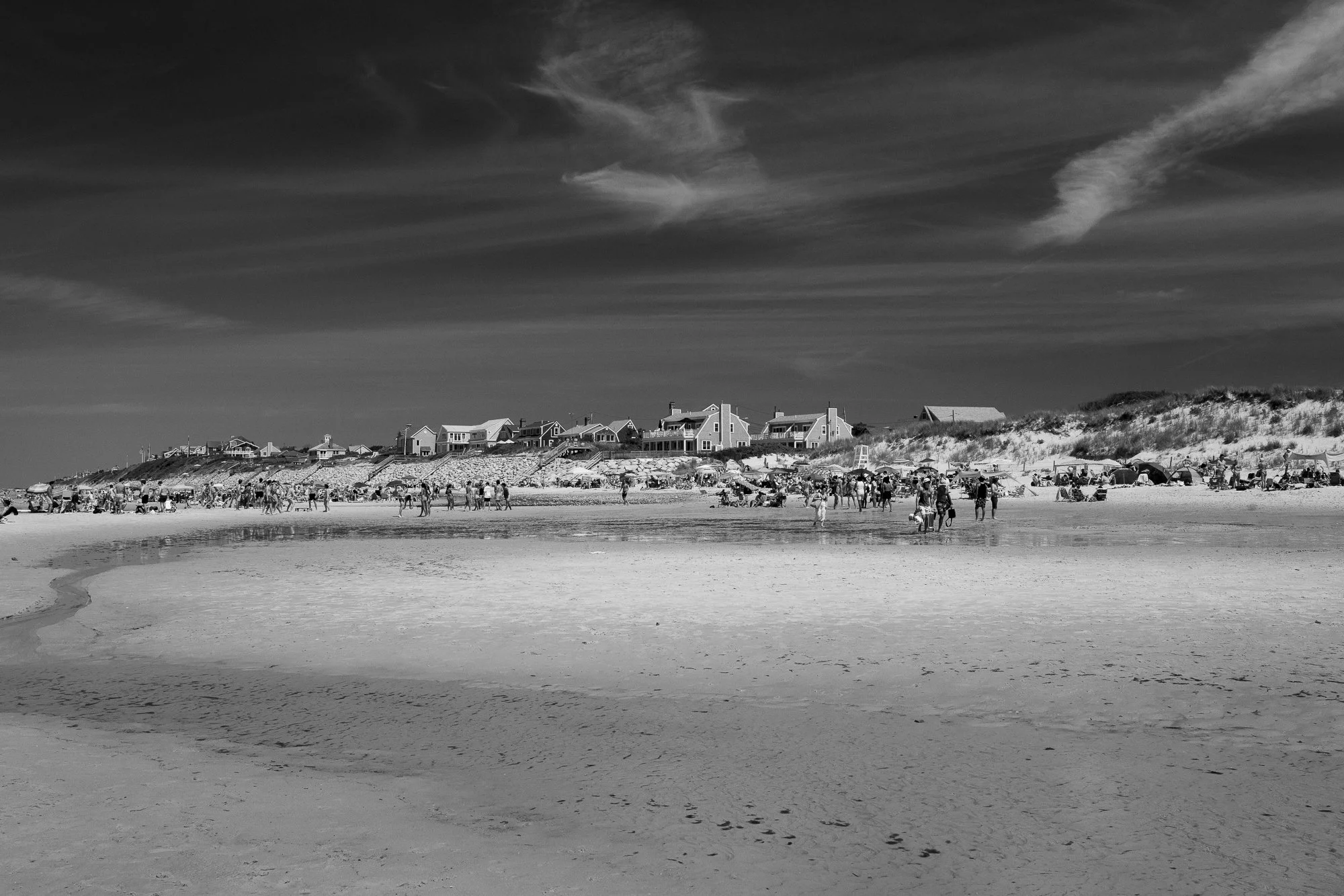 Black and white photo of Mayflower Beach on Cape Cod with people walking across shallow water at low tide