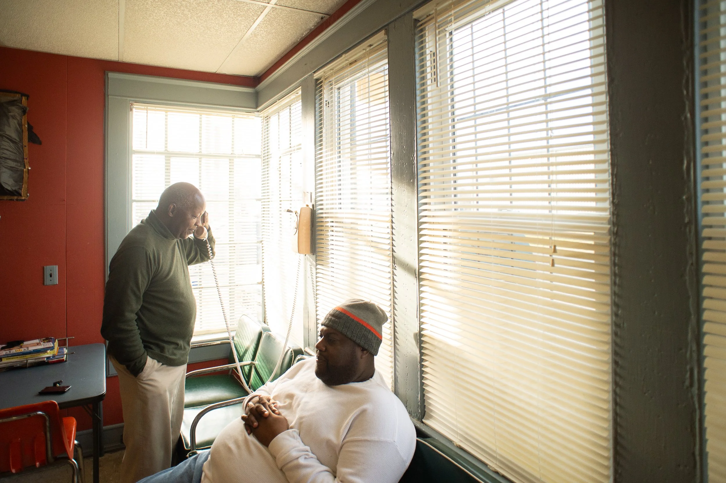 Two men sitting and talking near the window inside a barbershop in Maryland