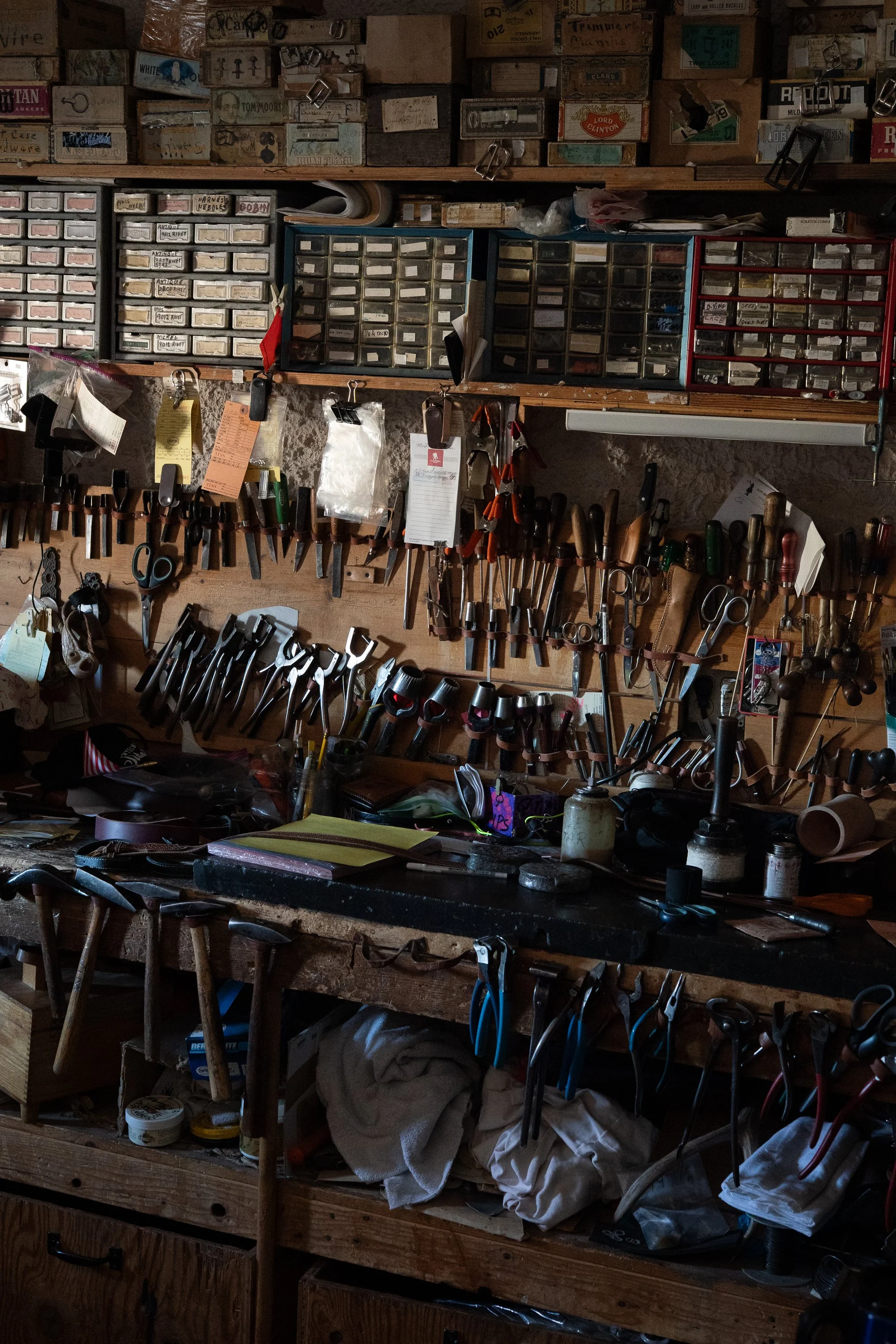 Leatherworking tools, scissors, pliers and small parts drawers arranged across a wooden workbench at City Shoe & Saddle Shop in Douglas, Wyoming.