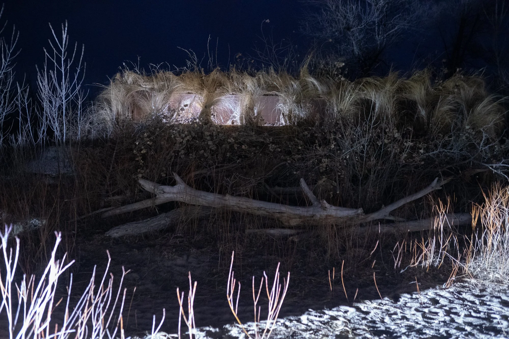 A camouflaged duck blind sits along the riverbank before sunrise