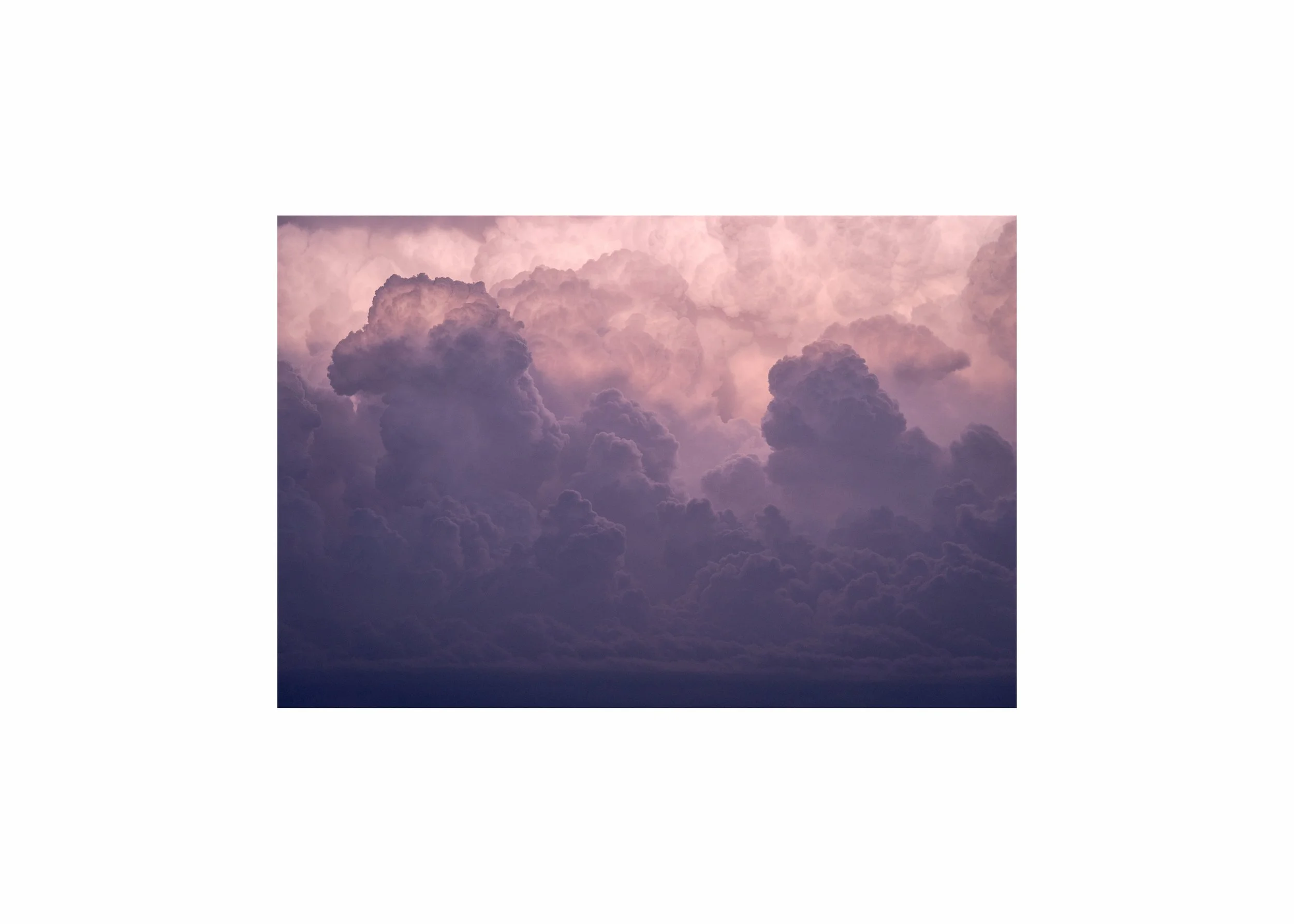 Dramatic amethyst storm clouds illuminated by pink sunset light.