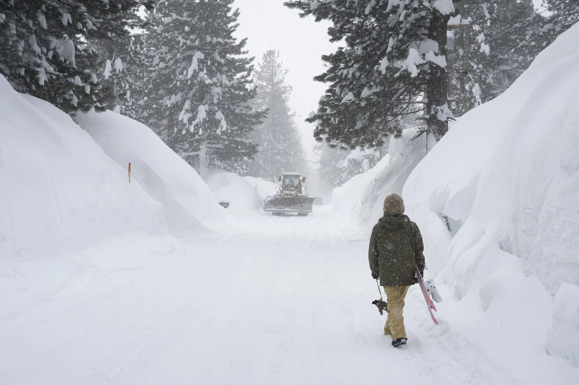A snowboarder walks down the street after a massive winter snow storm in Mammoth Lakes, California