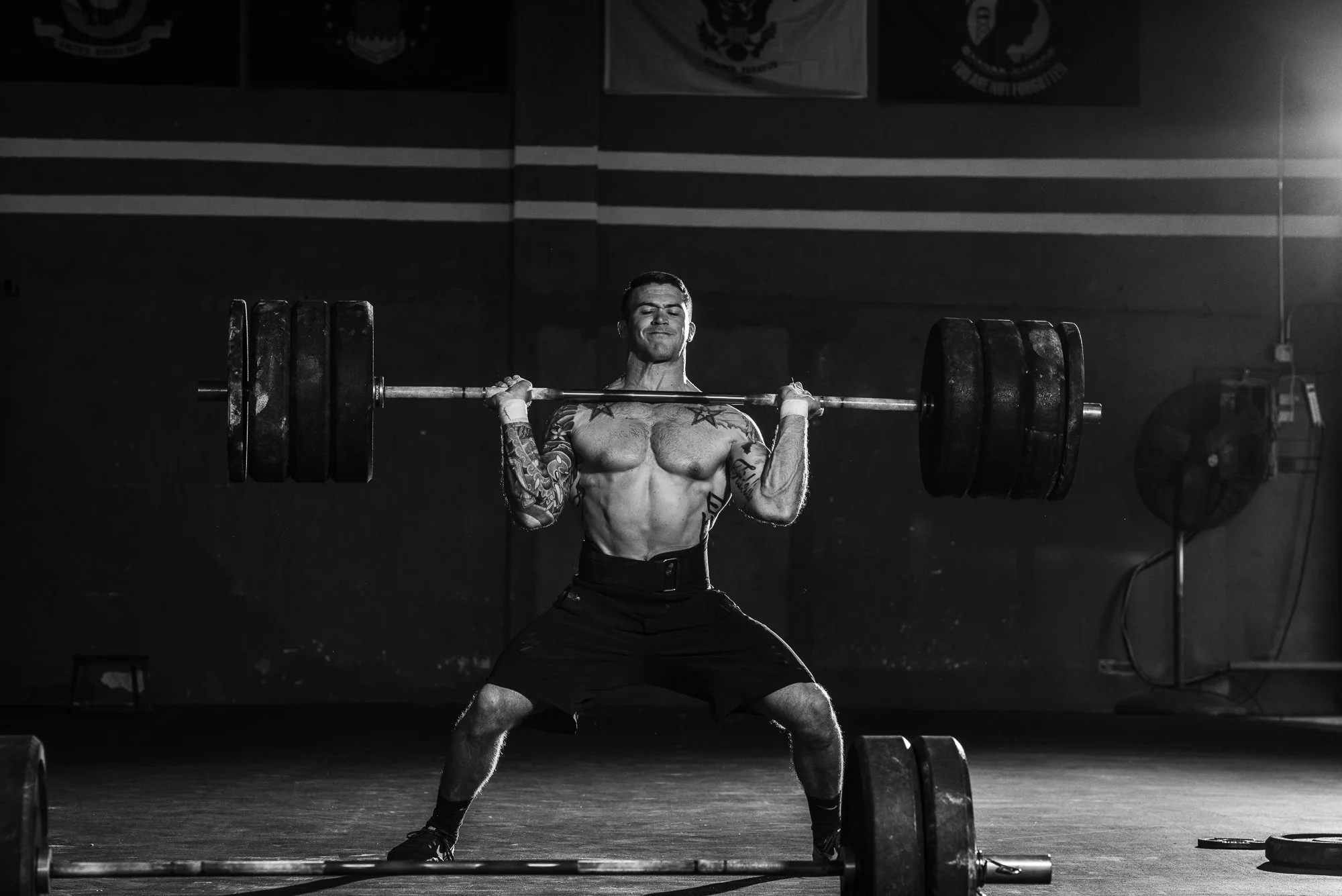 CrossFit athlete holding a heavily loaded barbell in the front rack position during a lift.