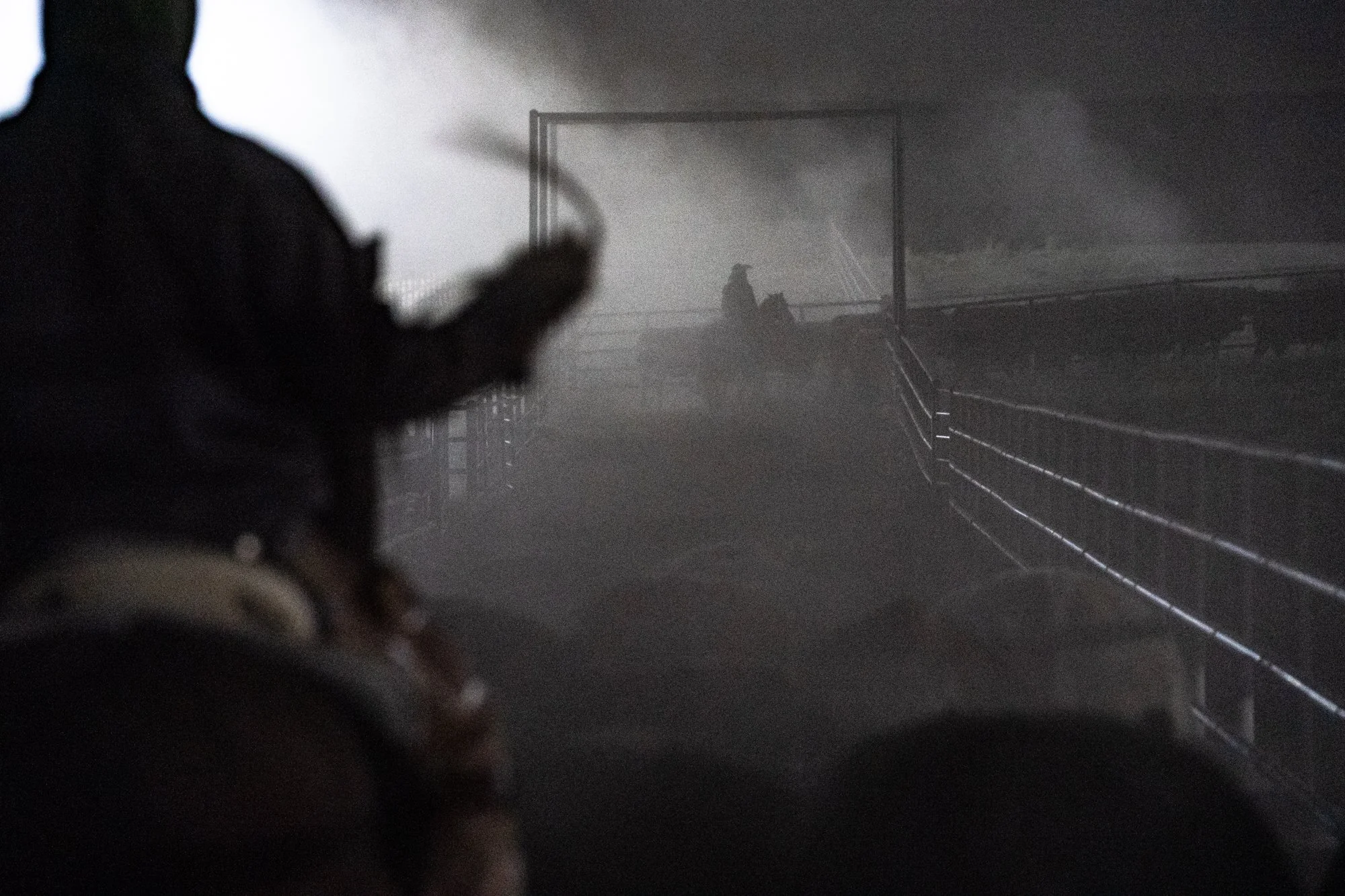Silhouetted pen rider on horseback rides through a dusty alley before sunrise at Magnum Feedyard in Colorado