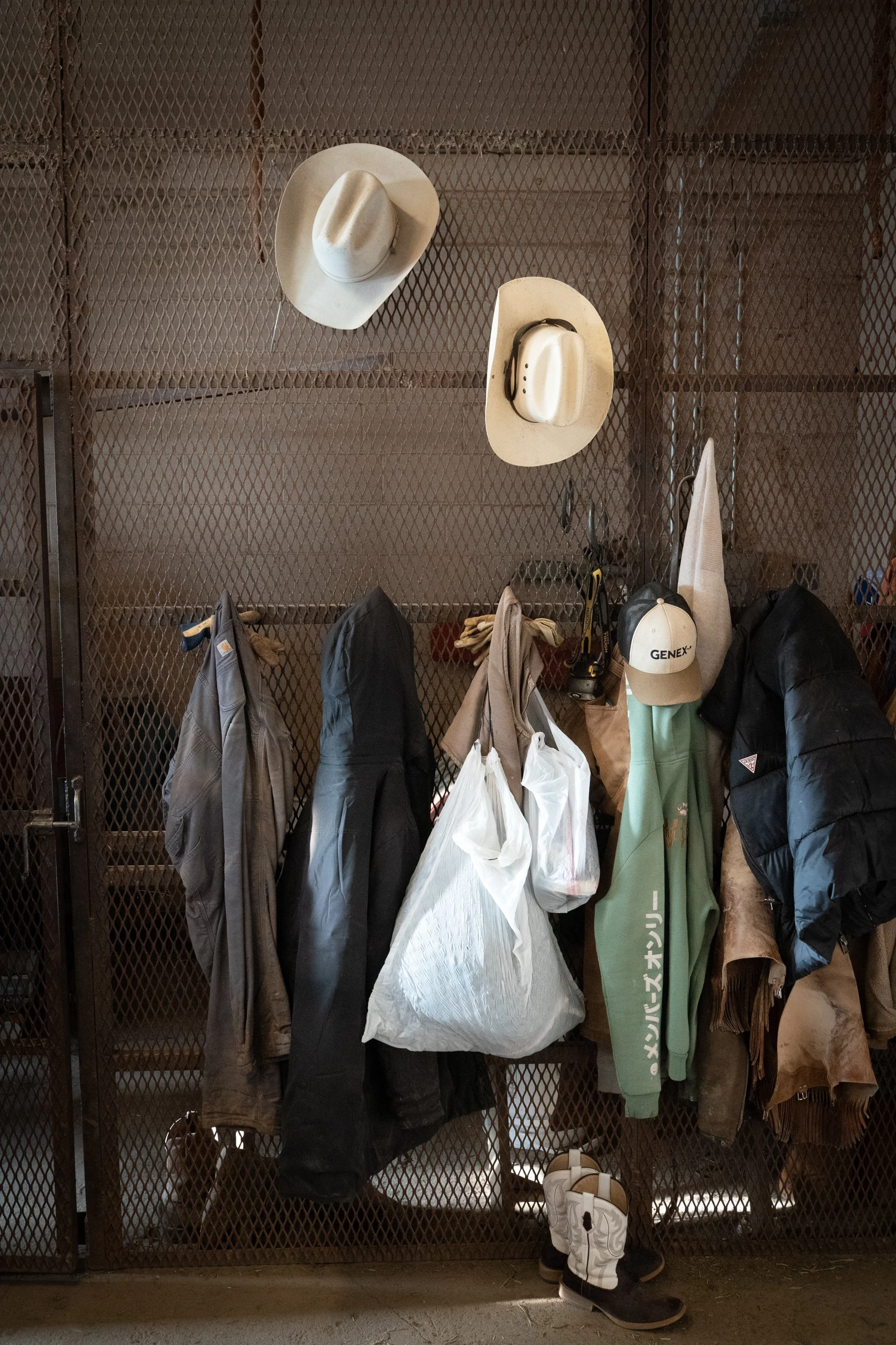 Cowboy hats, jackets, gloves, boots, and work gear hang inside the locker room at Magnum Feedyard in Colorado