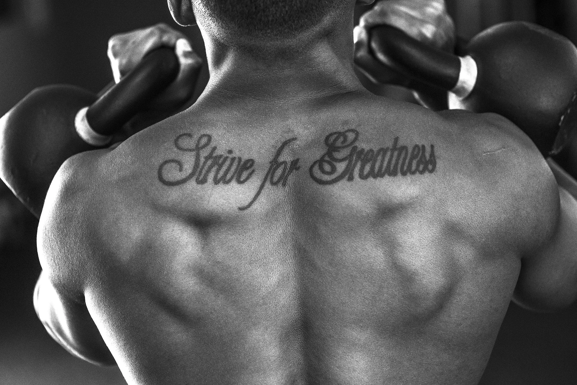black and white close up of muscular back with tattoo during workout