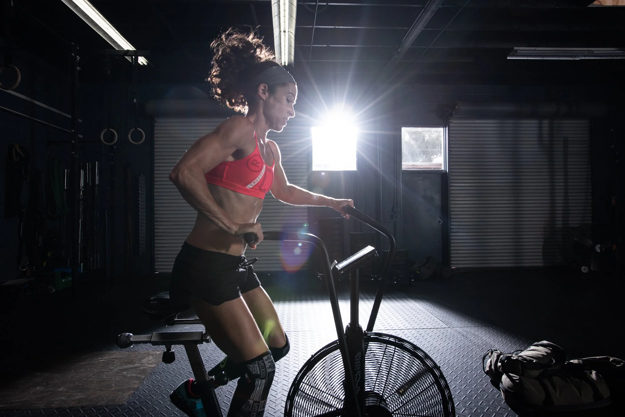 Female athlete performing barbell back squat in crossfit gym with strong back muscles visible