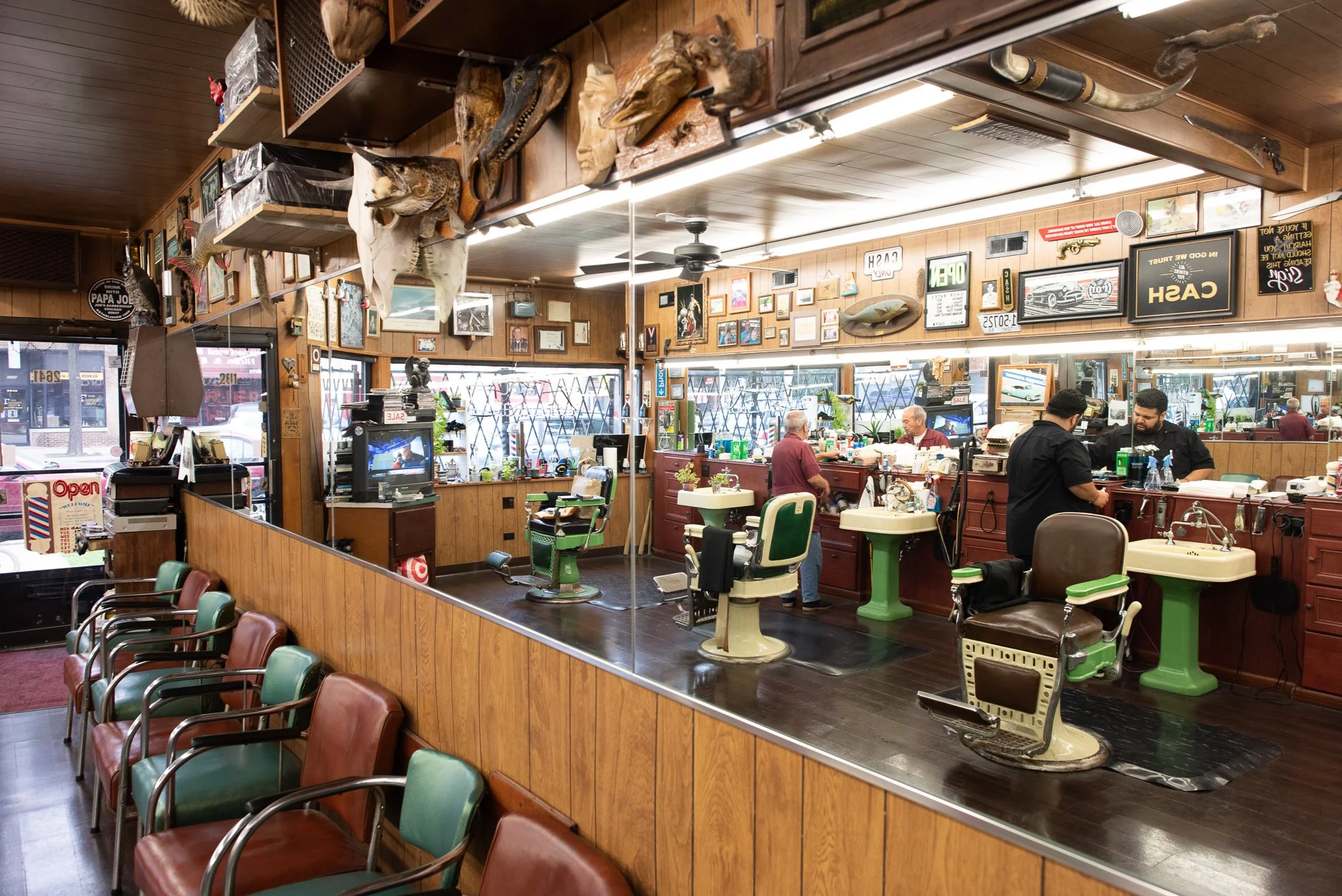 Wide interior view of Joe’s Barbershop in Chicago with barbers working and chairs along the wall