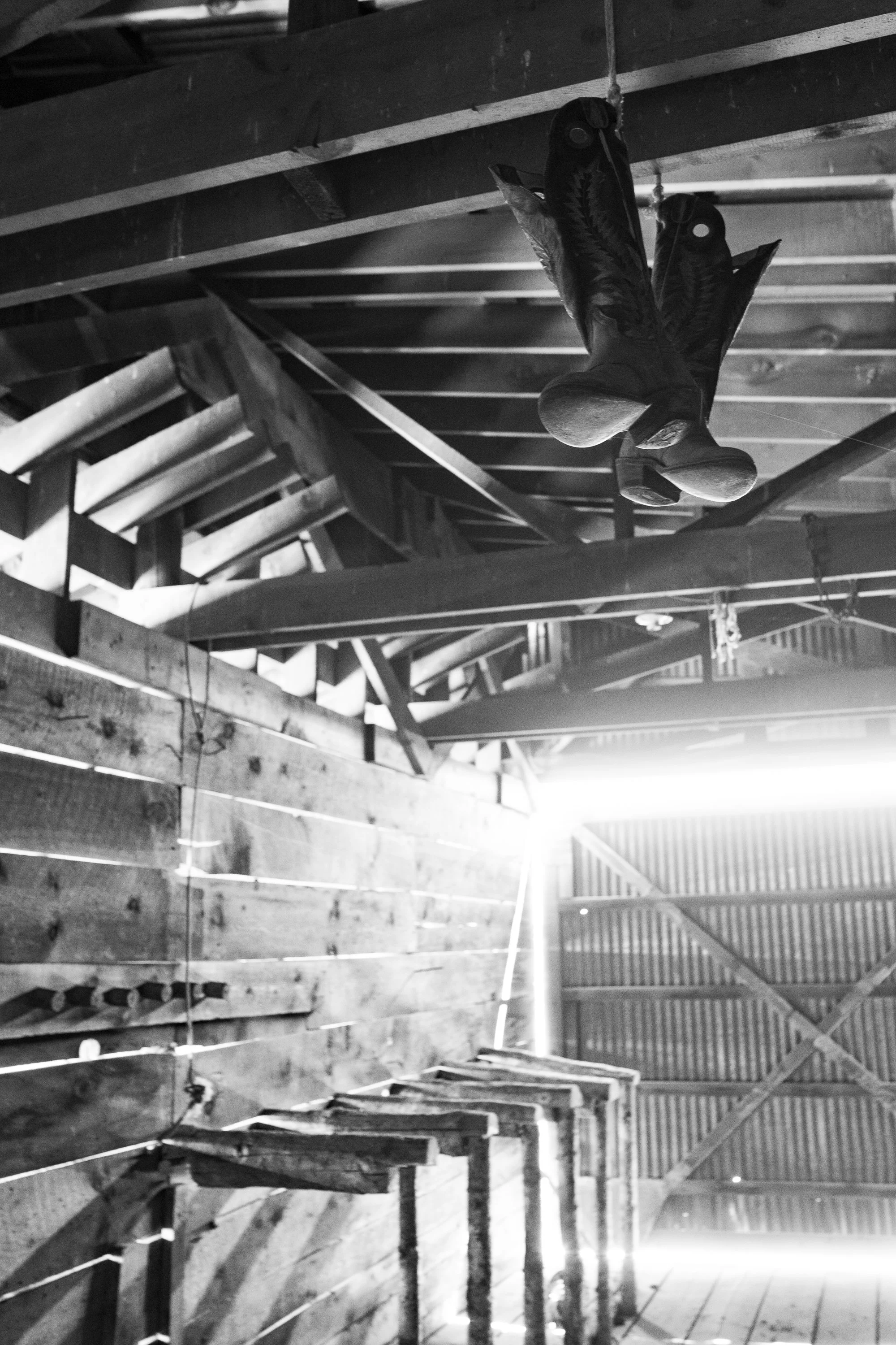 Cowboy boots hang from the rafters inside a wooden barn at the ZX Ranch in Oregon