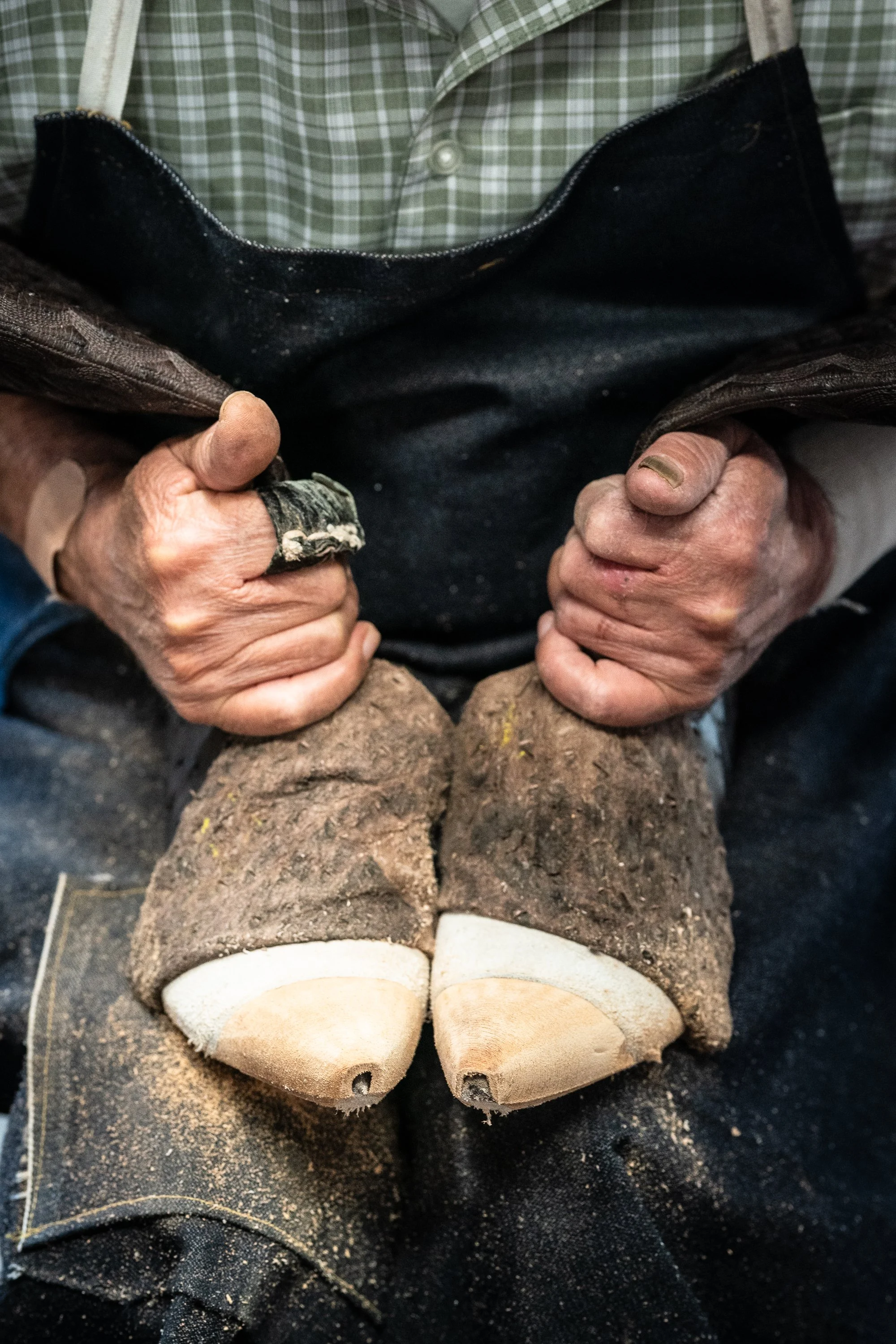 Bootmaker shaping leather over wooden lasts at ML Leddy’s boot shop