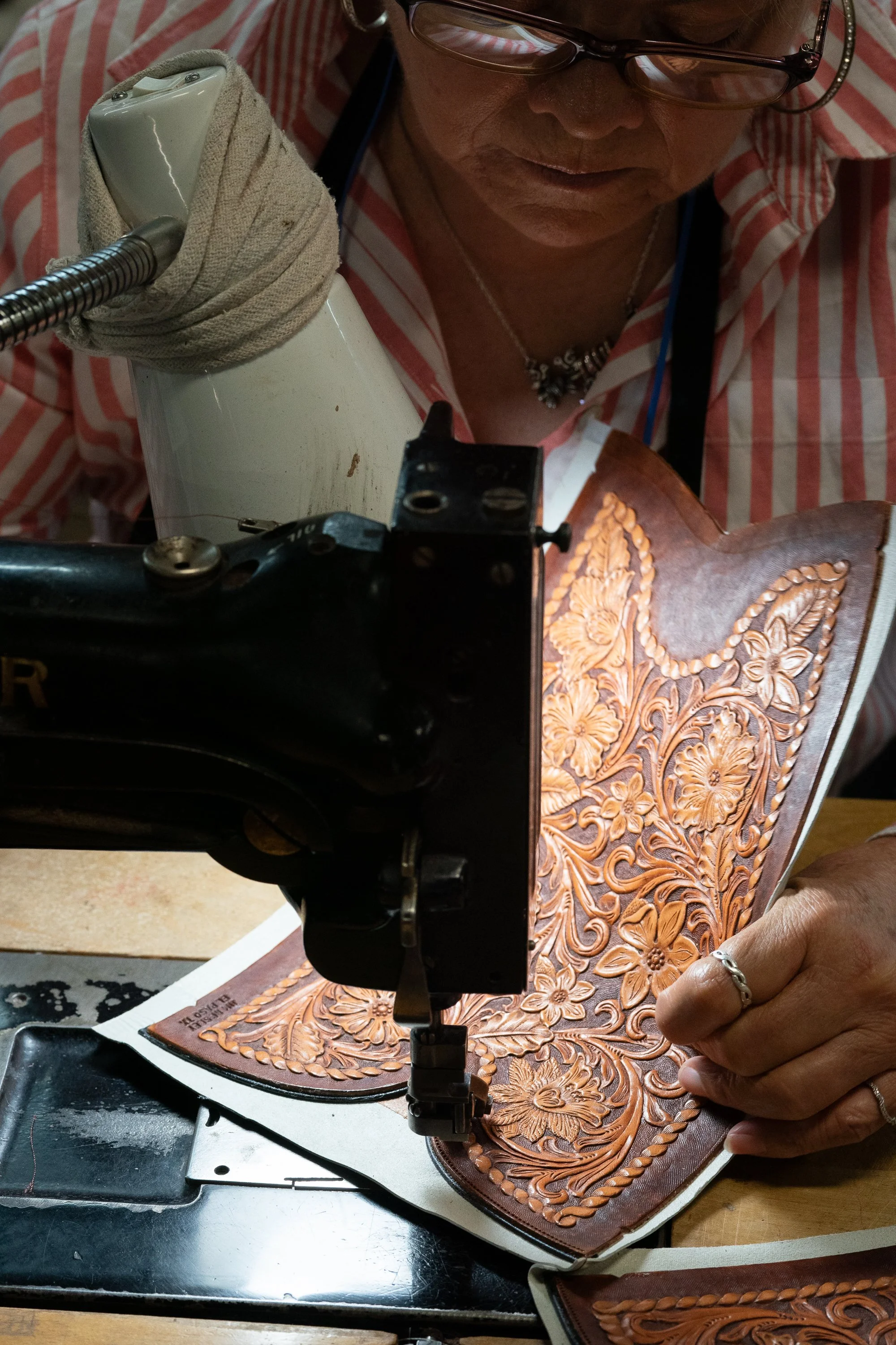 Craftswoman stitching decorative leather panels for cowboy boots at ML Leddy’s