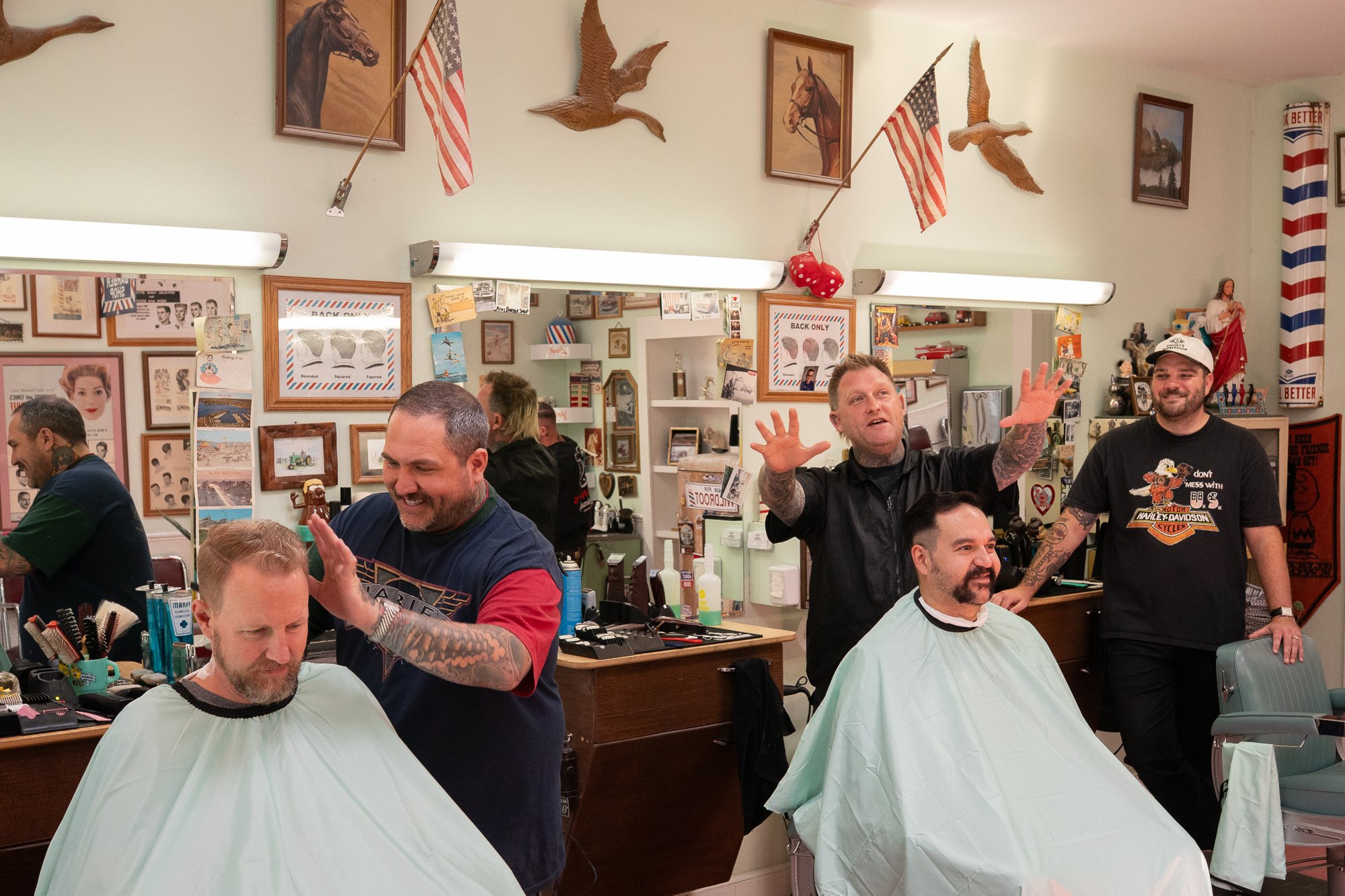 Barbers cutting hair inside Spanky’s Barbershop in Covington, Kentucky surrounded by framed artwork and traditional barber decor.