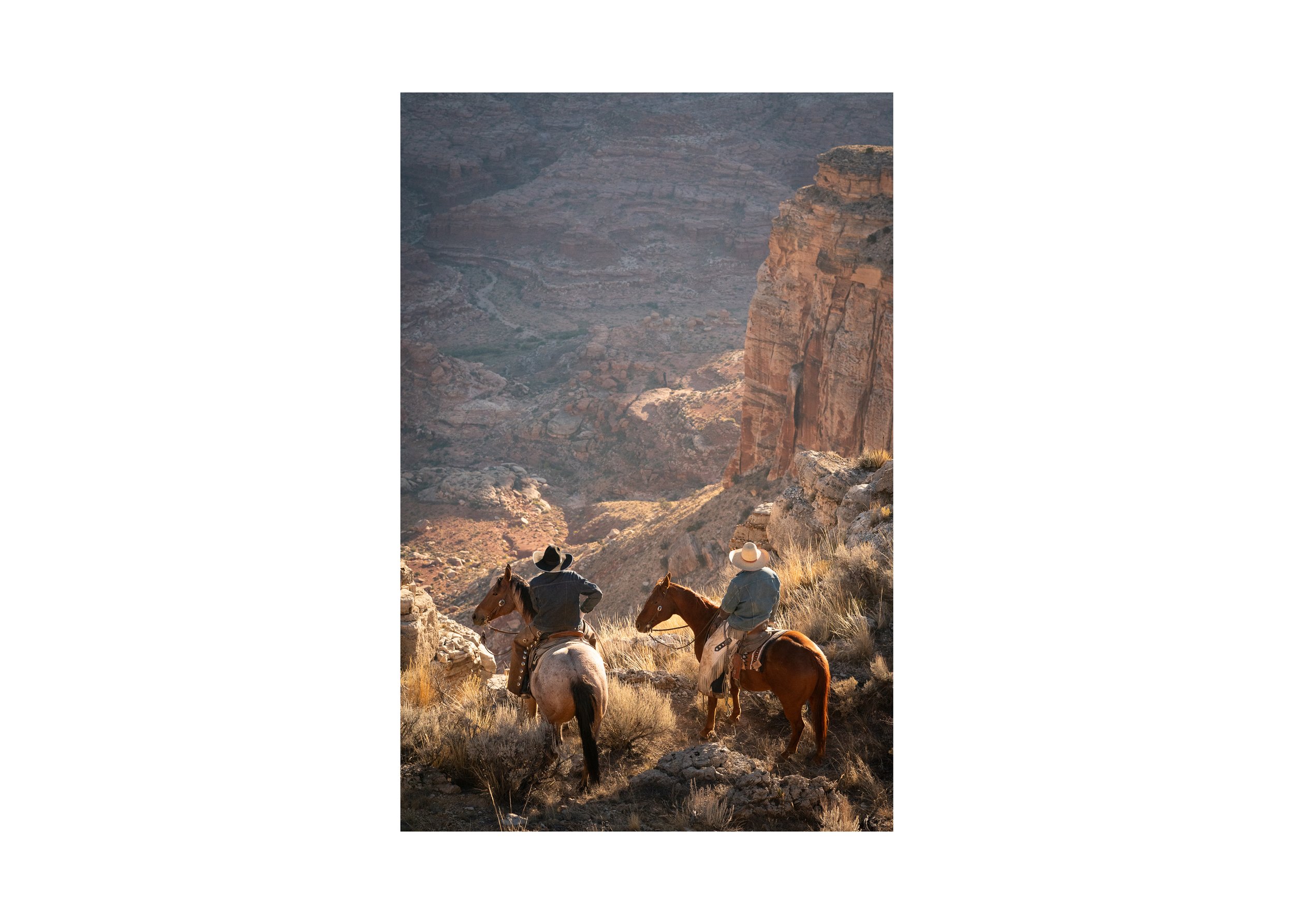 Two working cowboys on horseback overlooking a vast desert canyon at sunset, fine art Western photography print.